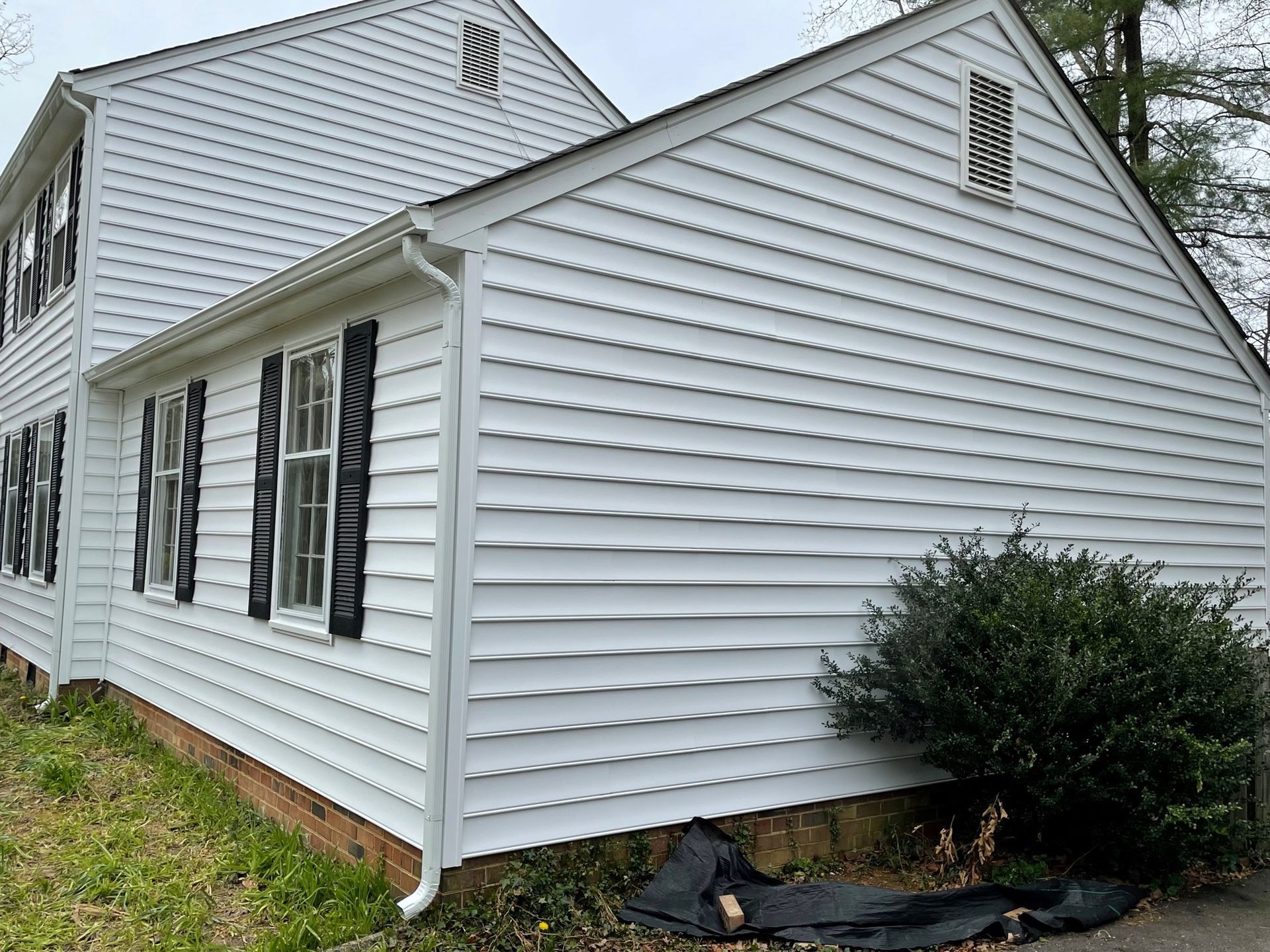 A white house with black shutters on the side of it.