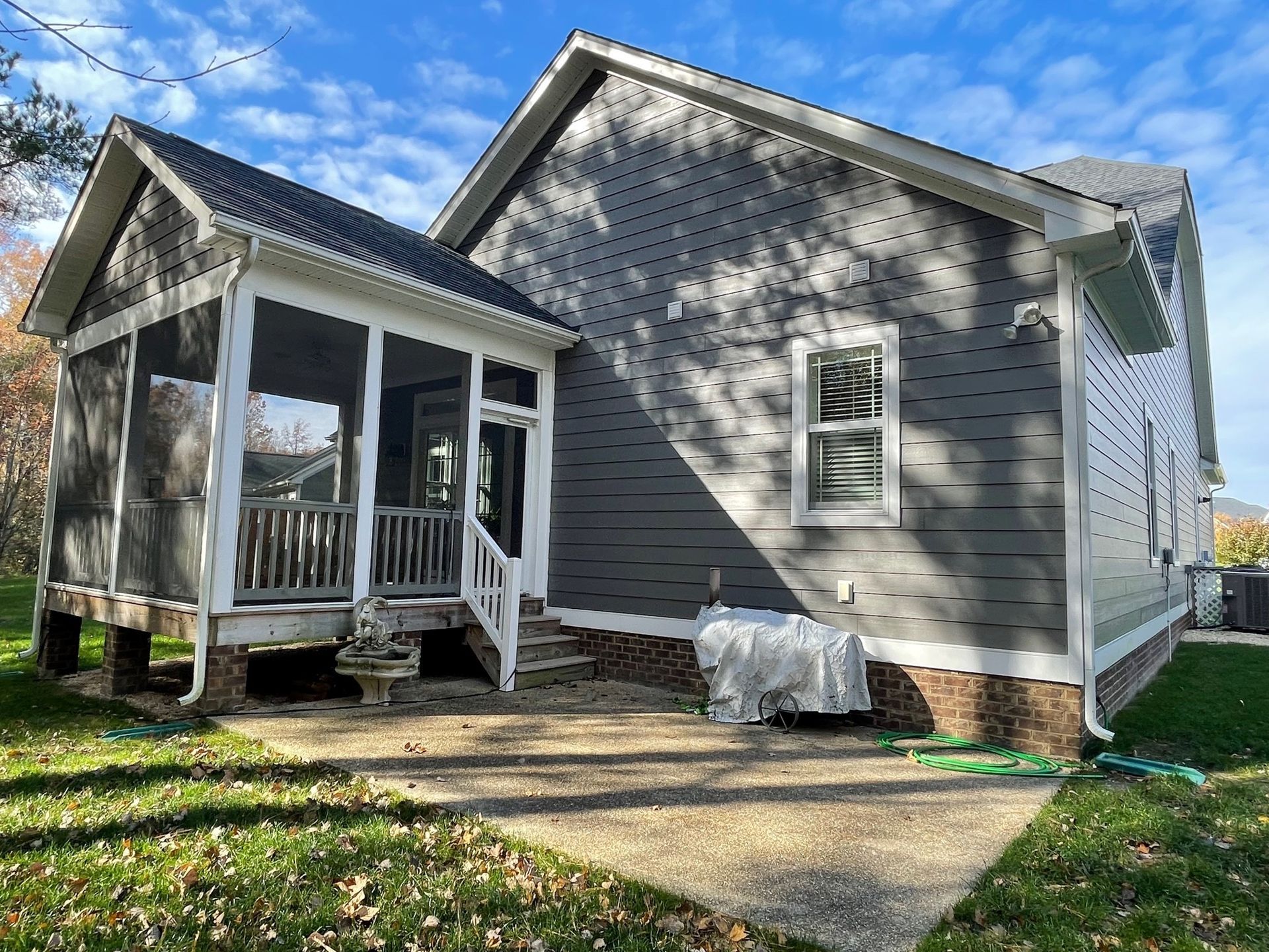 A small house with a screened in porch and a concrete patio.