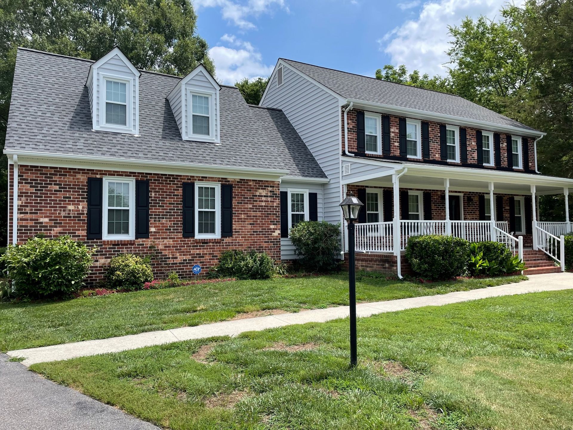A large brick house with a porch and black shutters