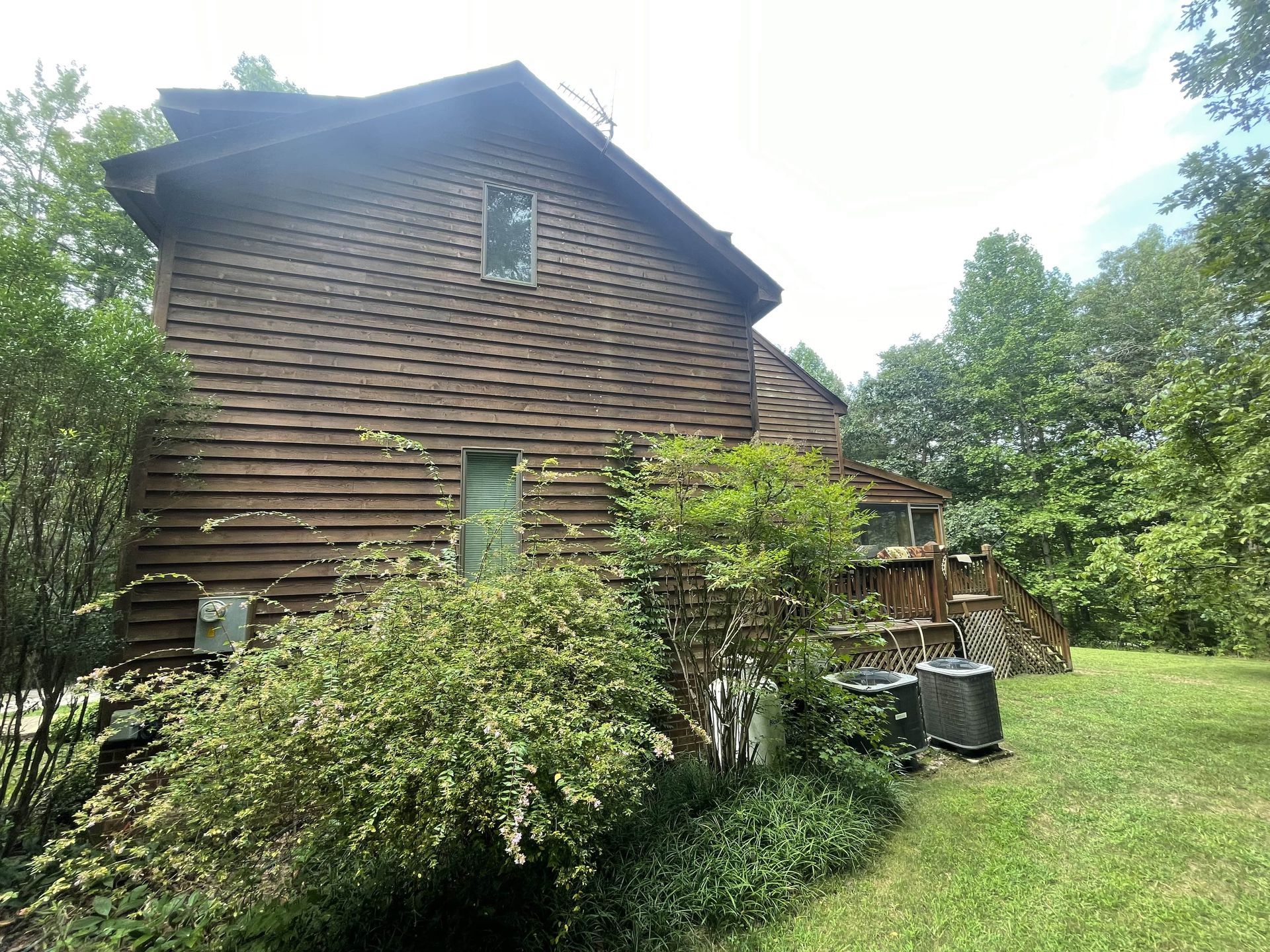 A large wooden house with a lot of trees in the background.