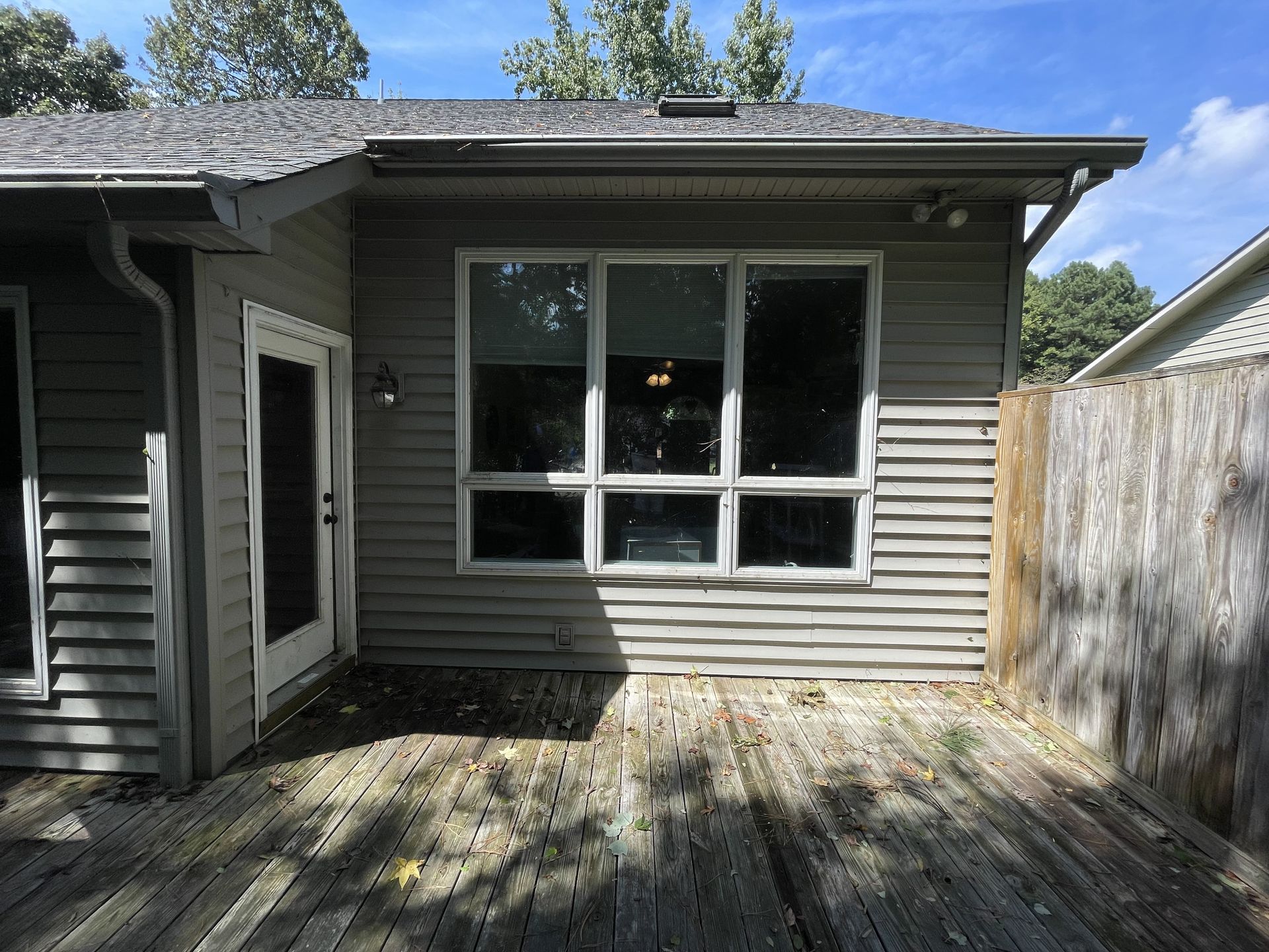 The back of a house with a wooden deck and a fence.