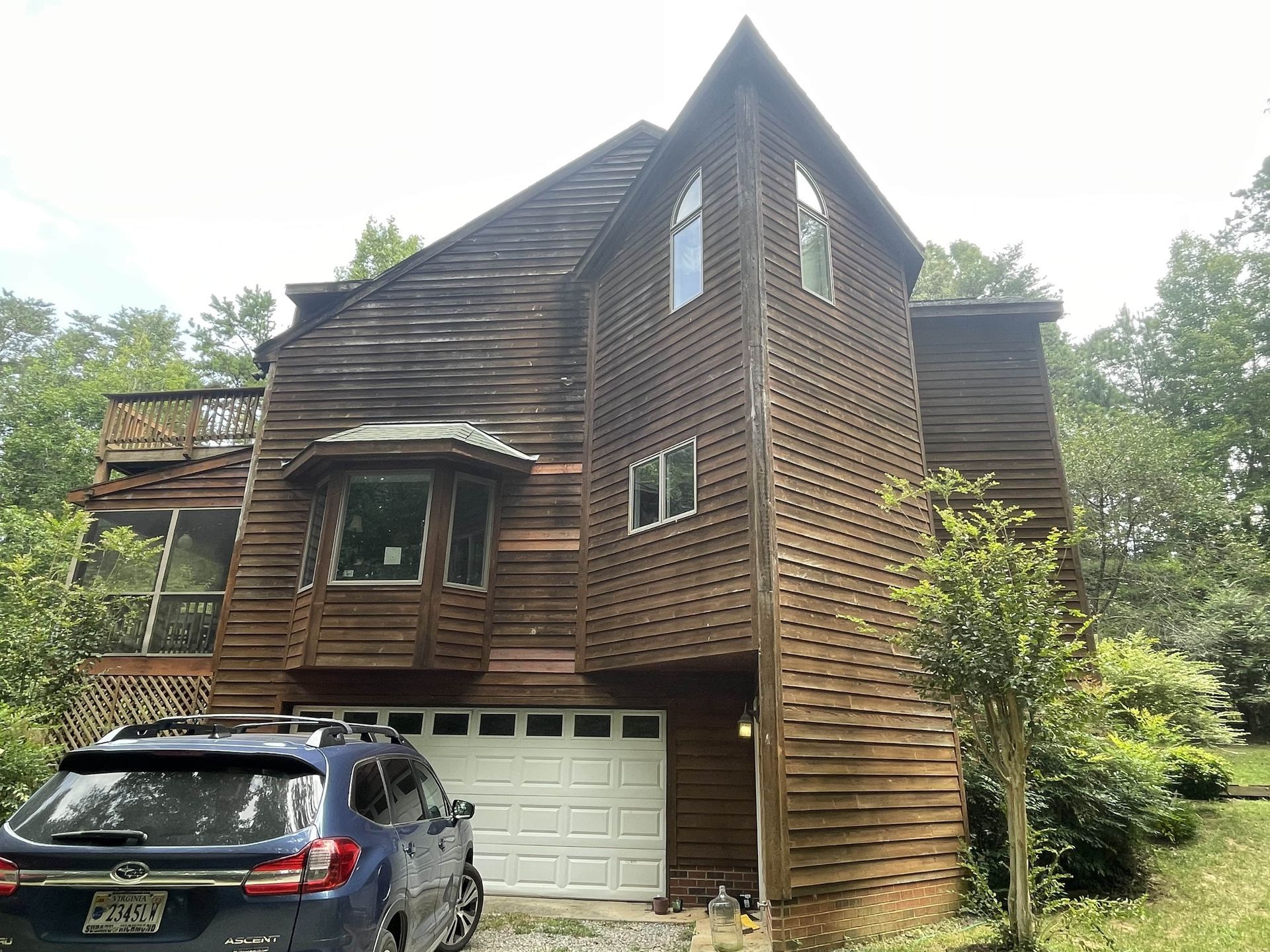 A large wooden house with a car parked in front of it.