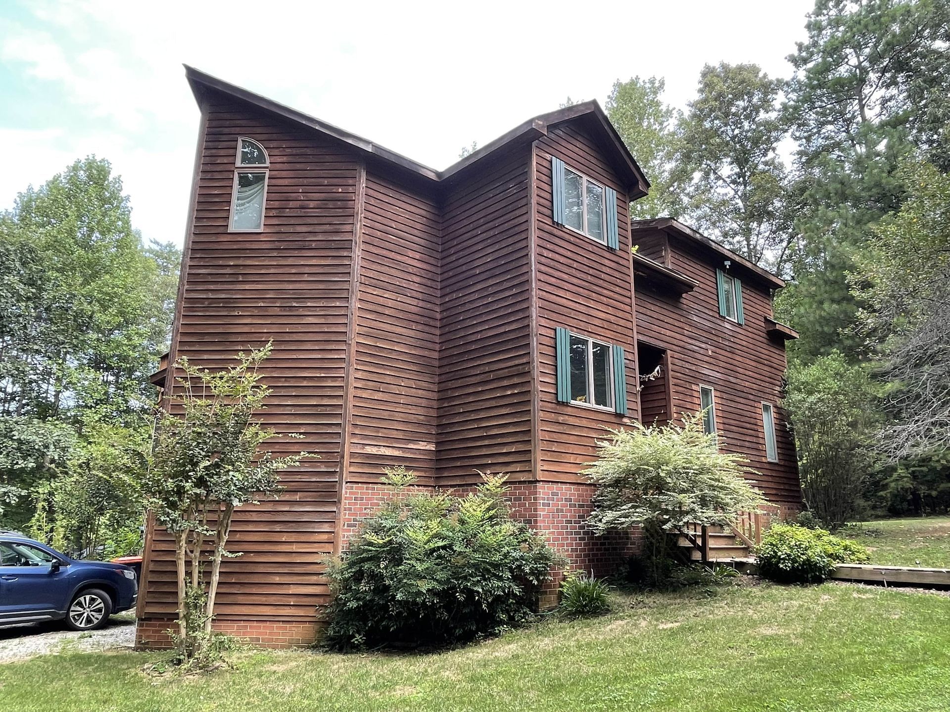 A large wooden house with a blue car parked in front of it.