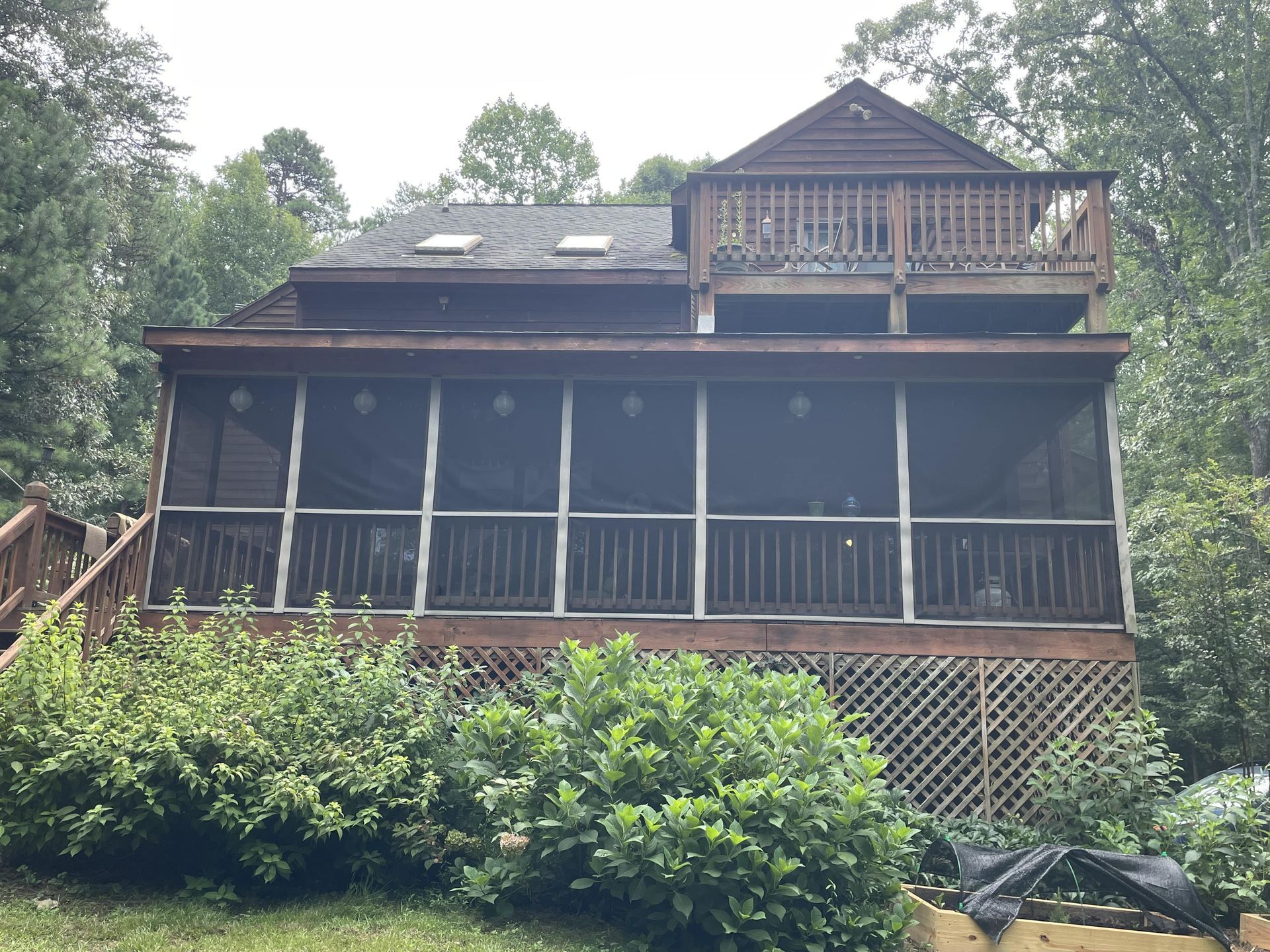 A house with a screened in porch is surrounded by trees.