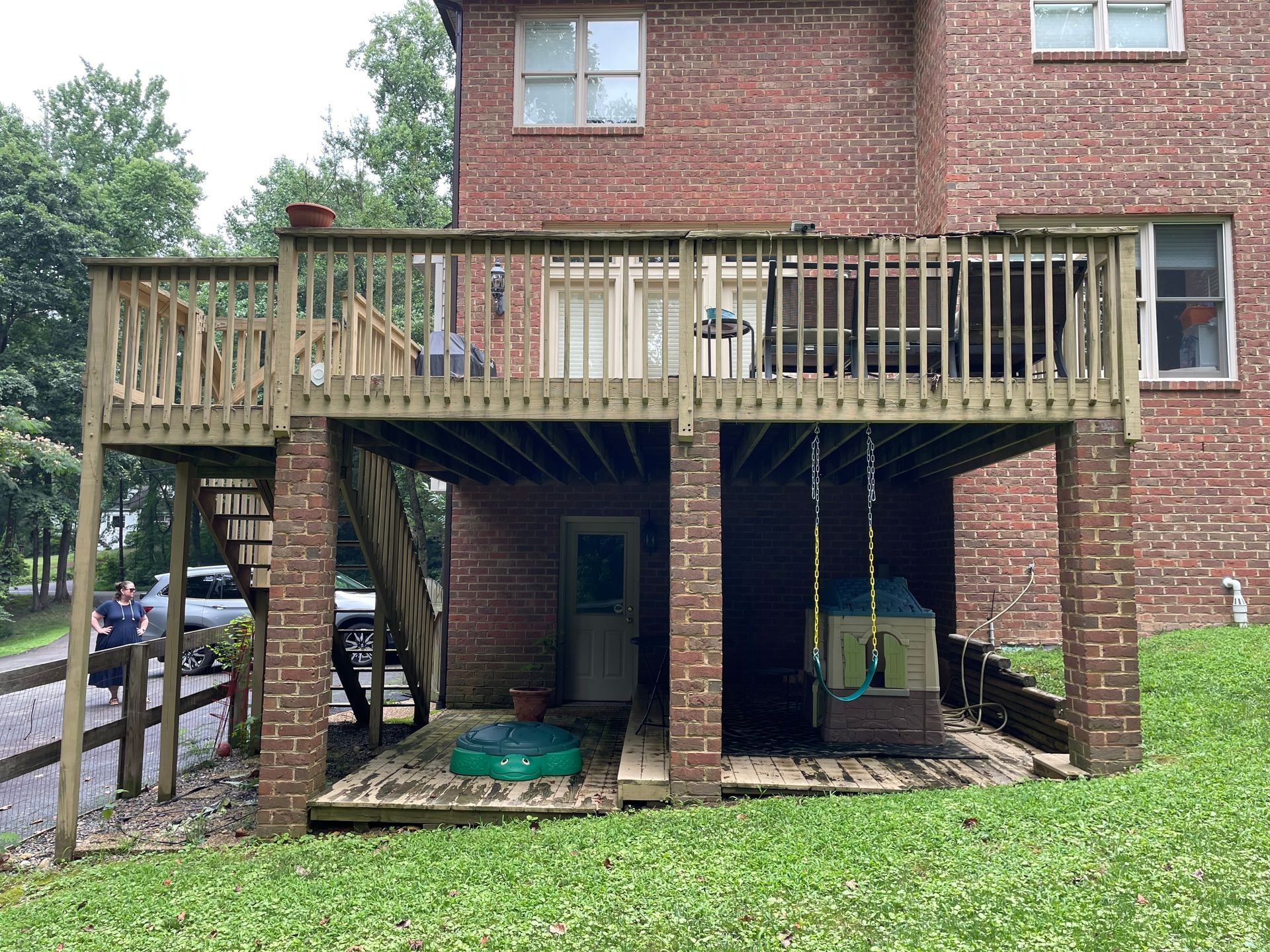A brick house with a wooden deck in the backyard.