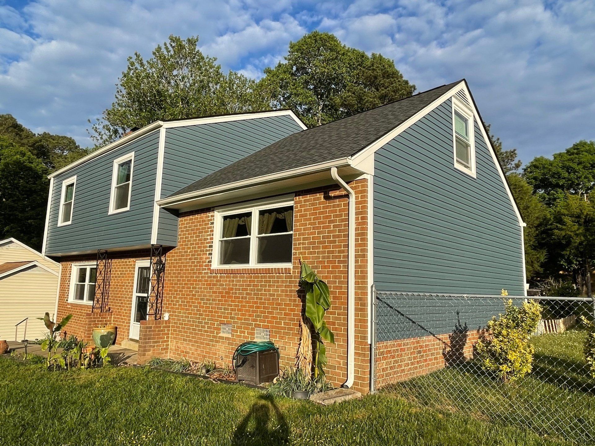 A brick house with a blue siding and a white trim