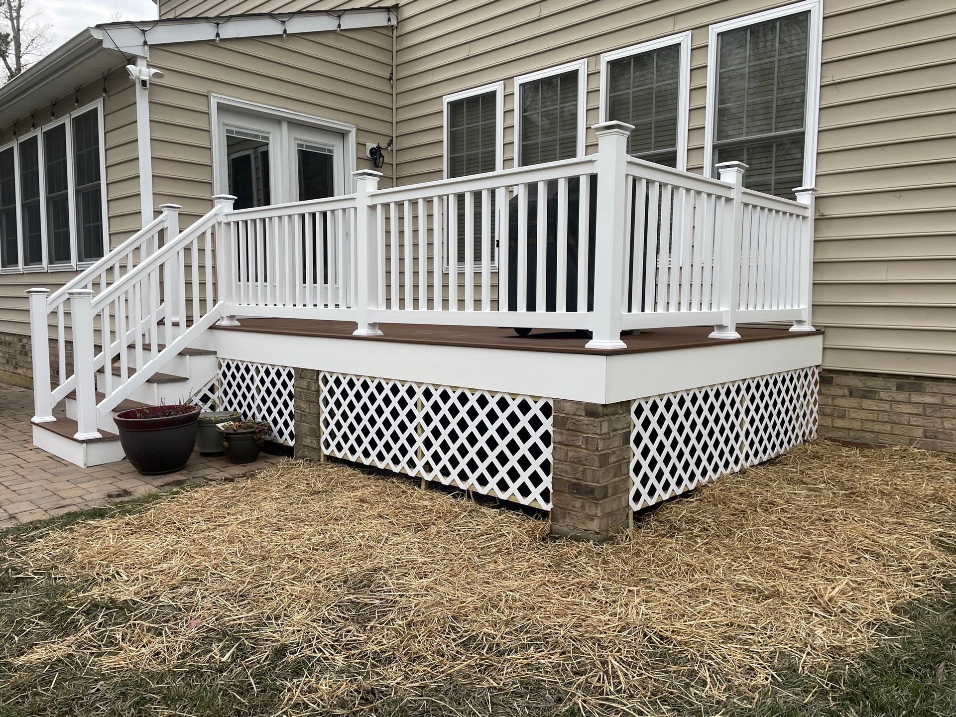 A white deck with stairs leading up to it is in front of a house.