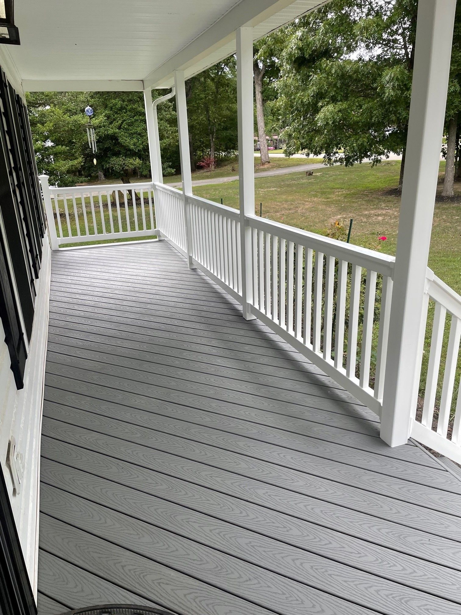 A large porch with a white railing and a gray deck.