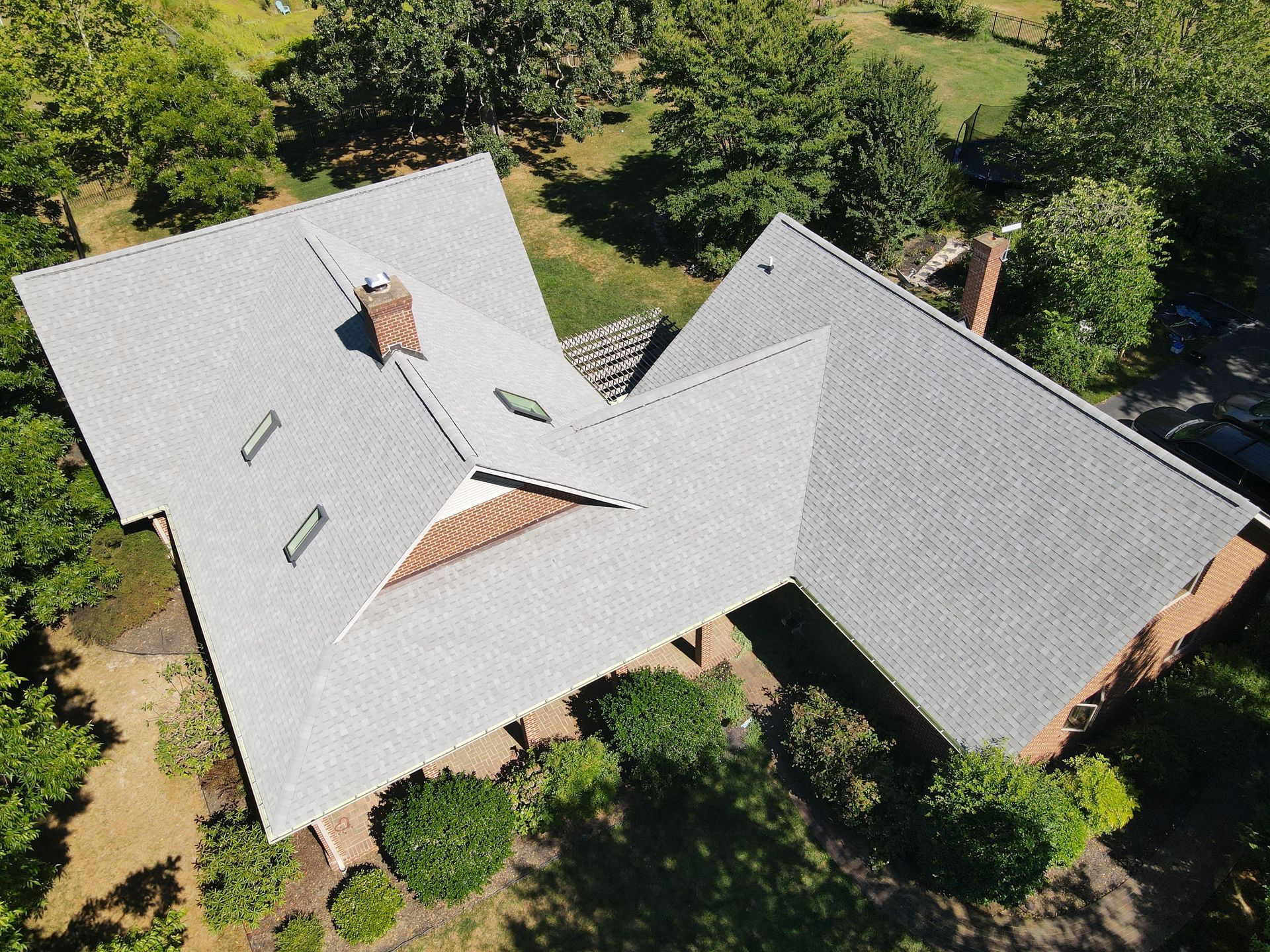 An aerial view of a house with a gray roof surrounded by trees.