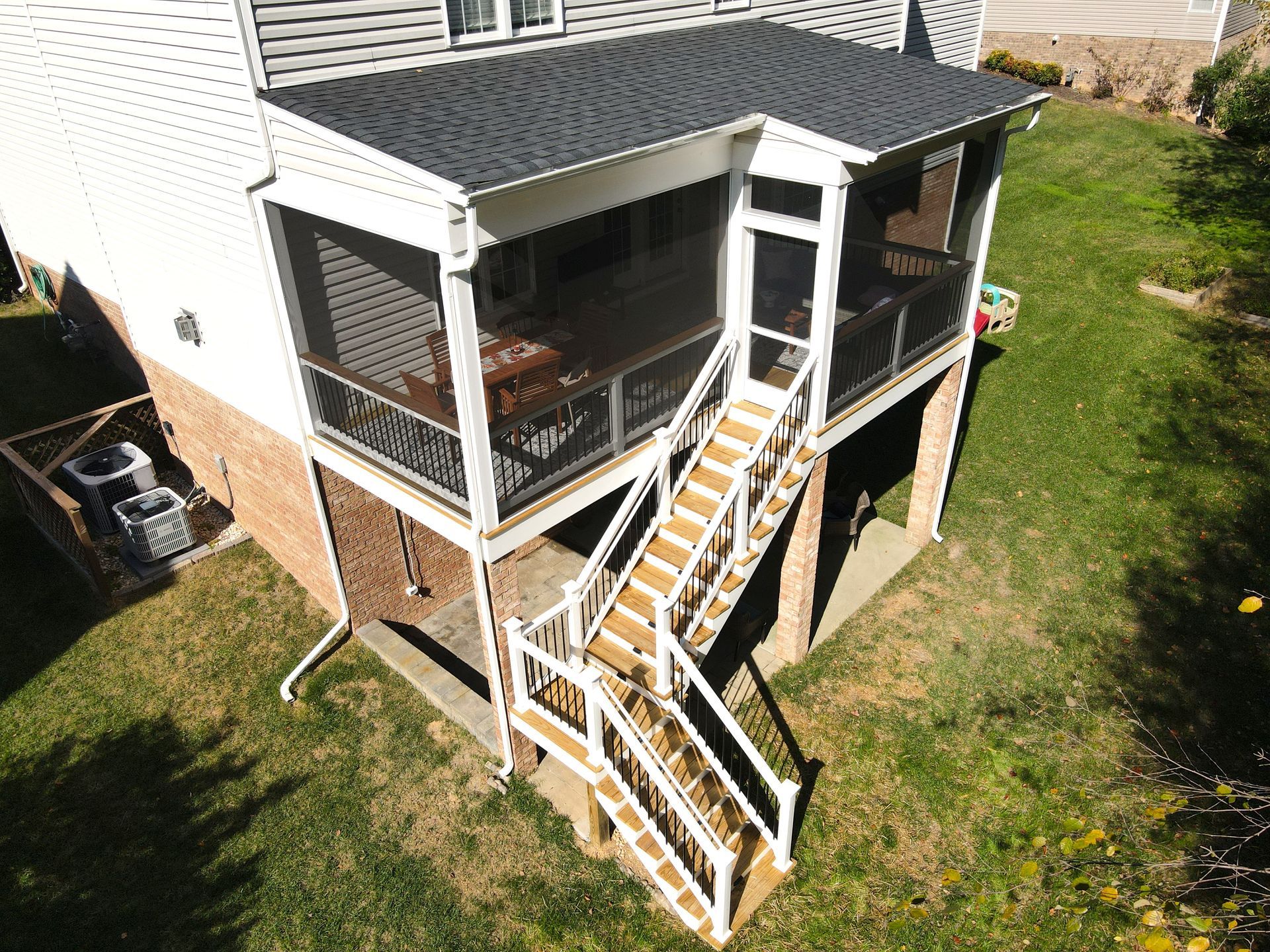 An aerial view of a house with a screened in porch and stairs.
