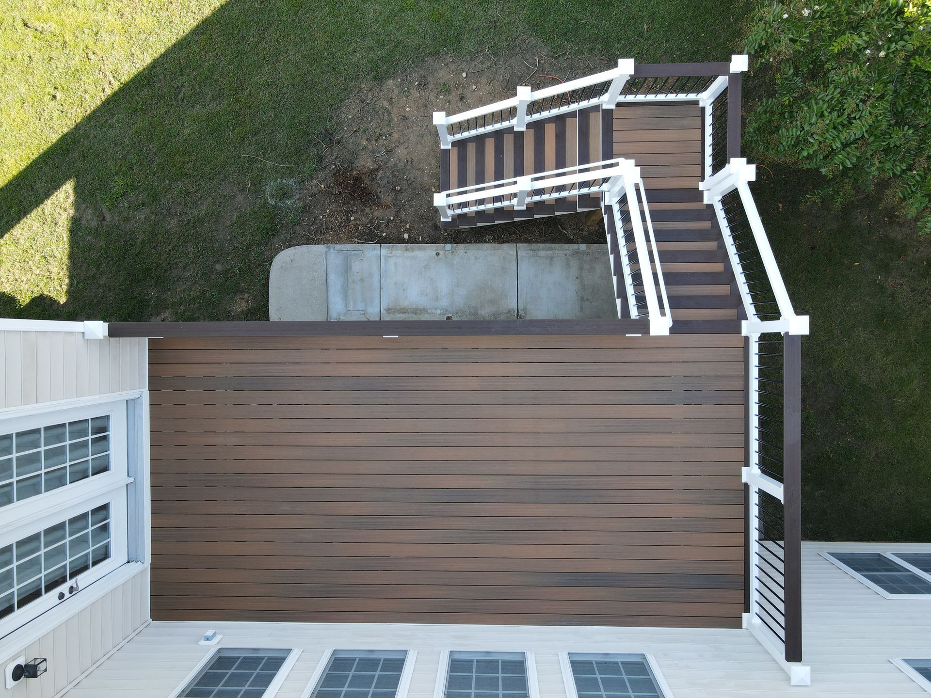Overhead view of a composite deck with stairs leading to a yard, brown and white railings.