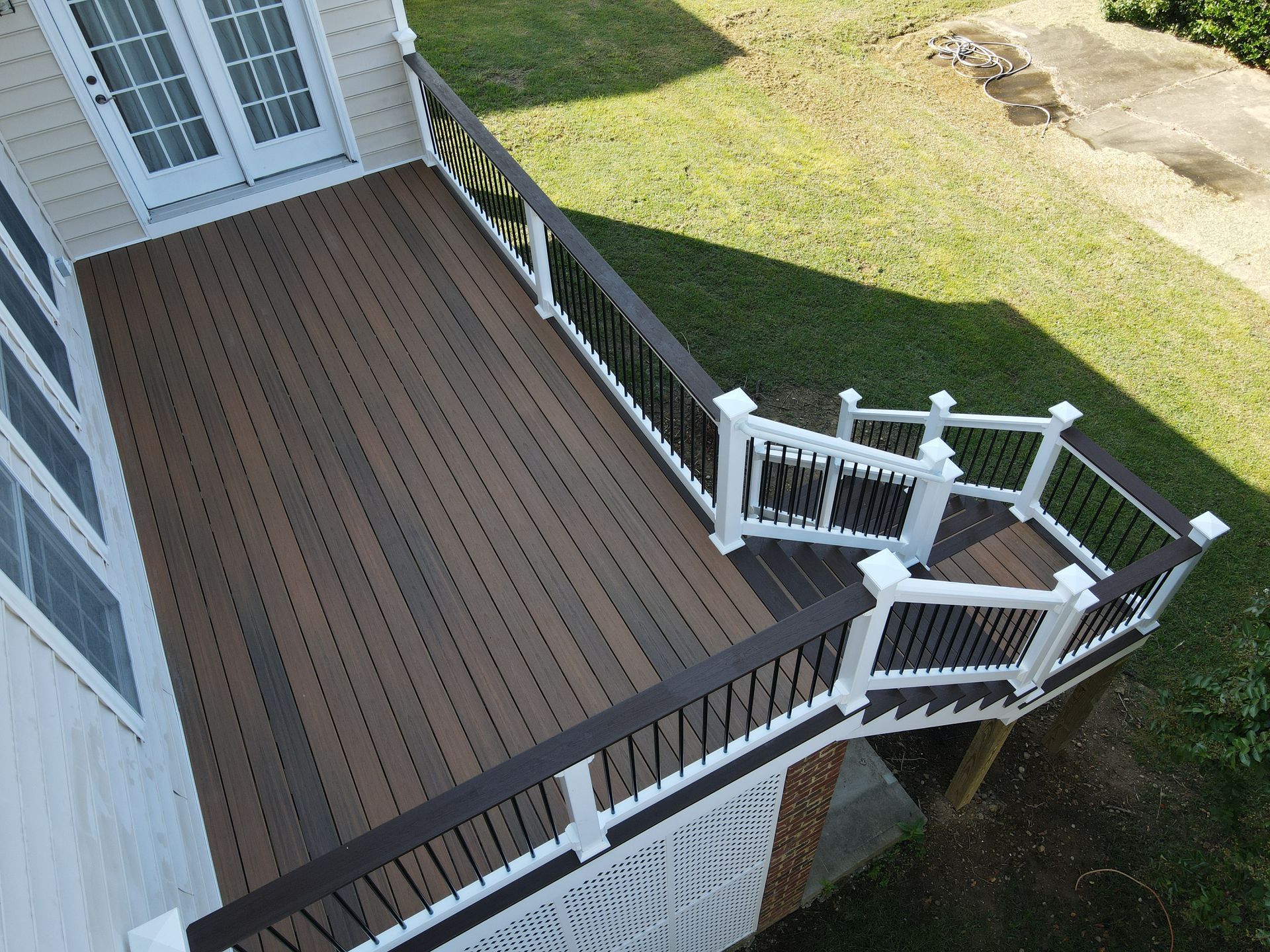 Overhead view of a multi-level deck with brown and gray composite decking, white railing, and black spindles.