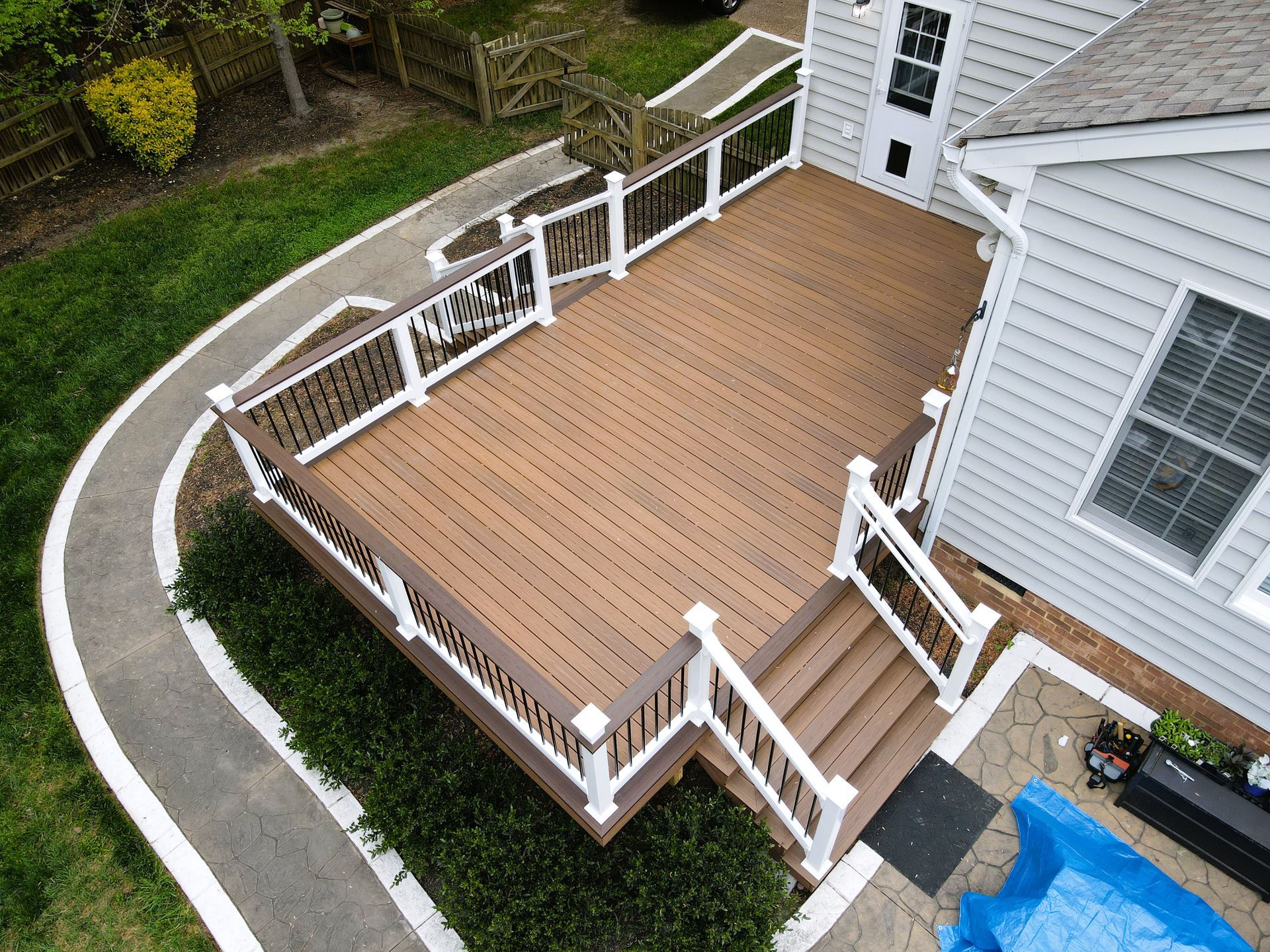 An aerial view of a wooden deck with white railings in front of a house.