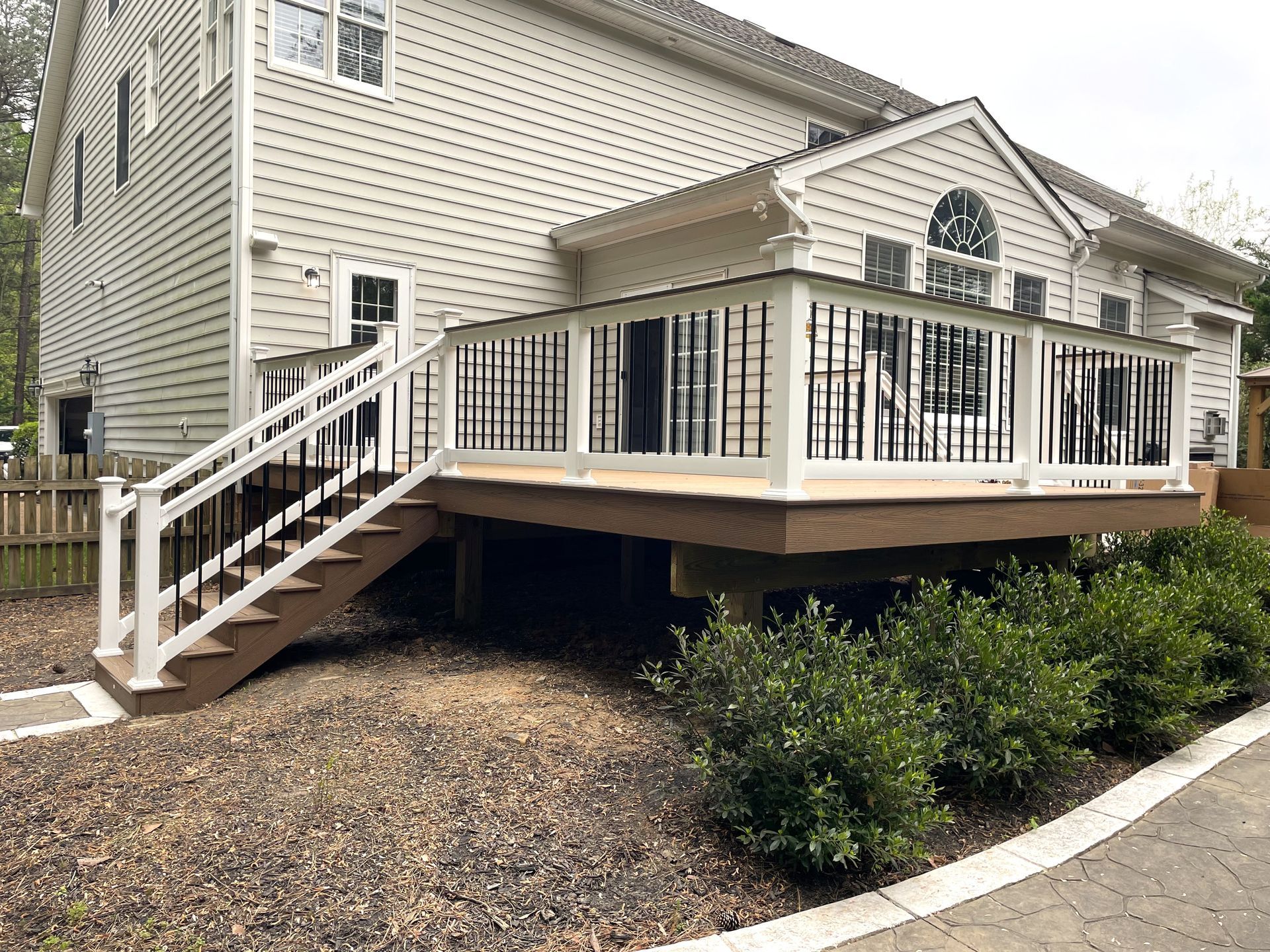A large white house with a large deck and stairs.