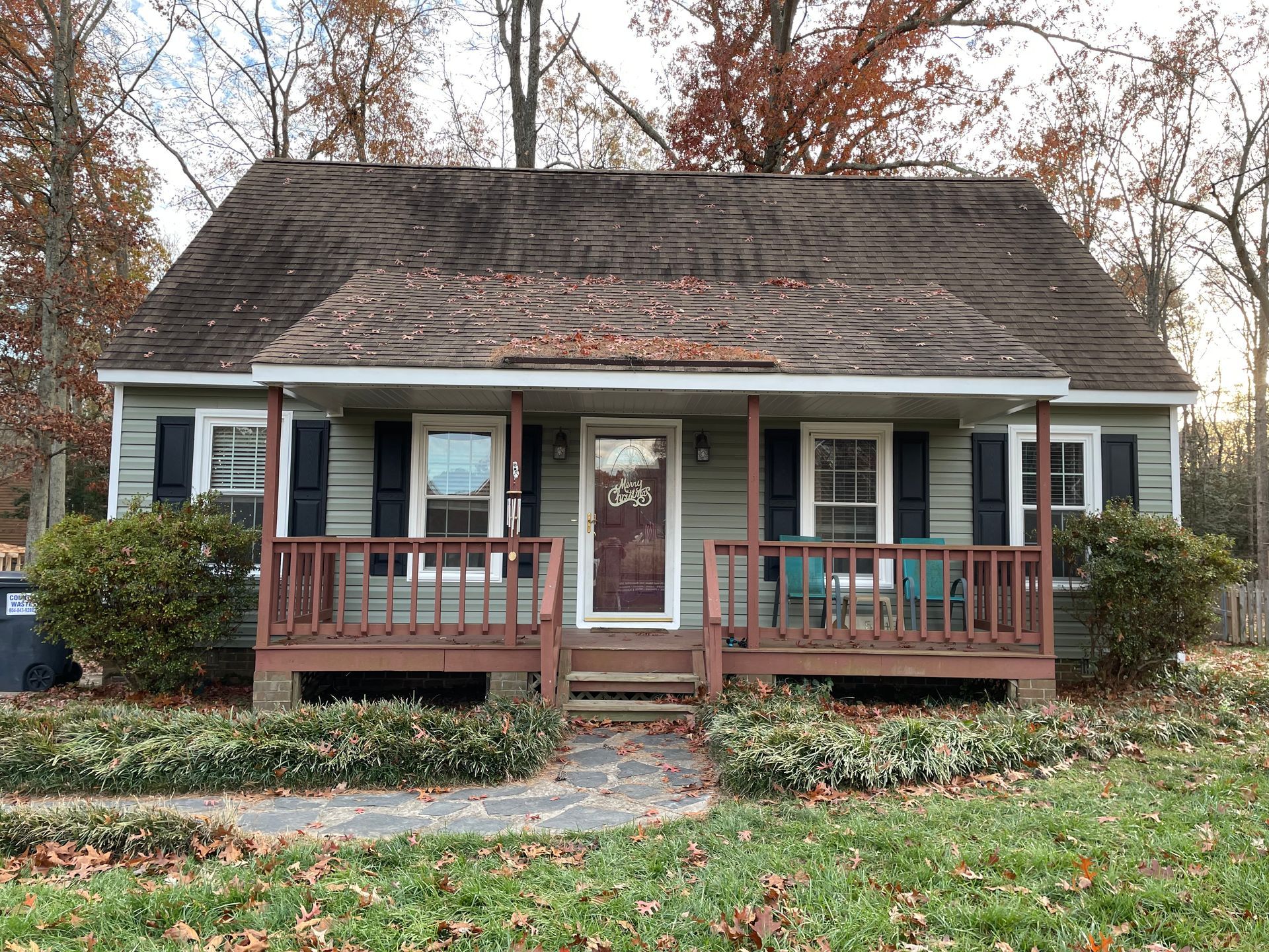 A house with a porch and a roof that is covered in leaves.