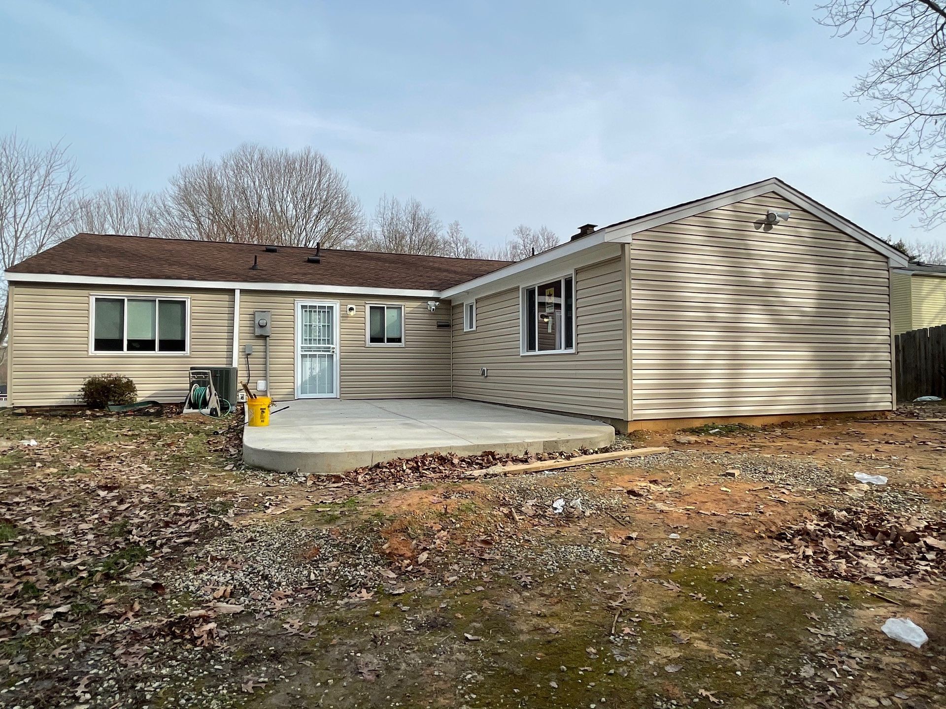 The back of a house with a patio in front of it.