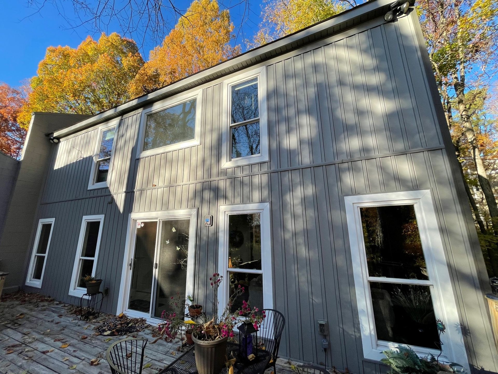 A house with a lot of windows and a patio in front of it.