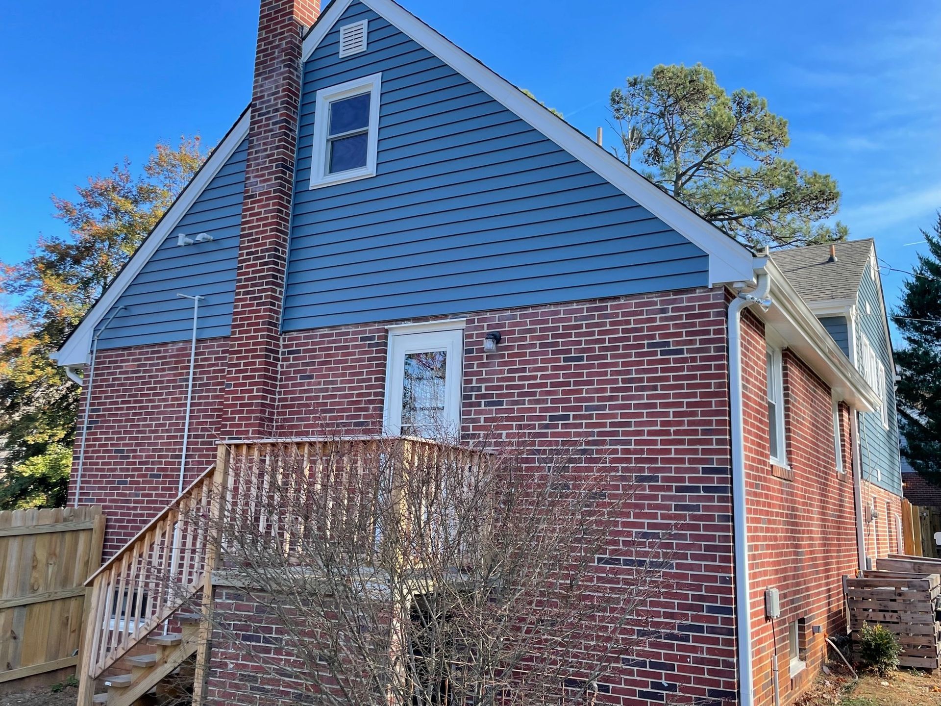A brick house with a blue siding and a deck.