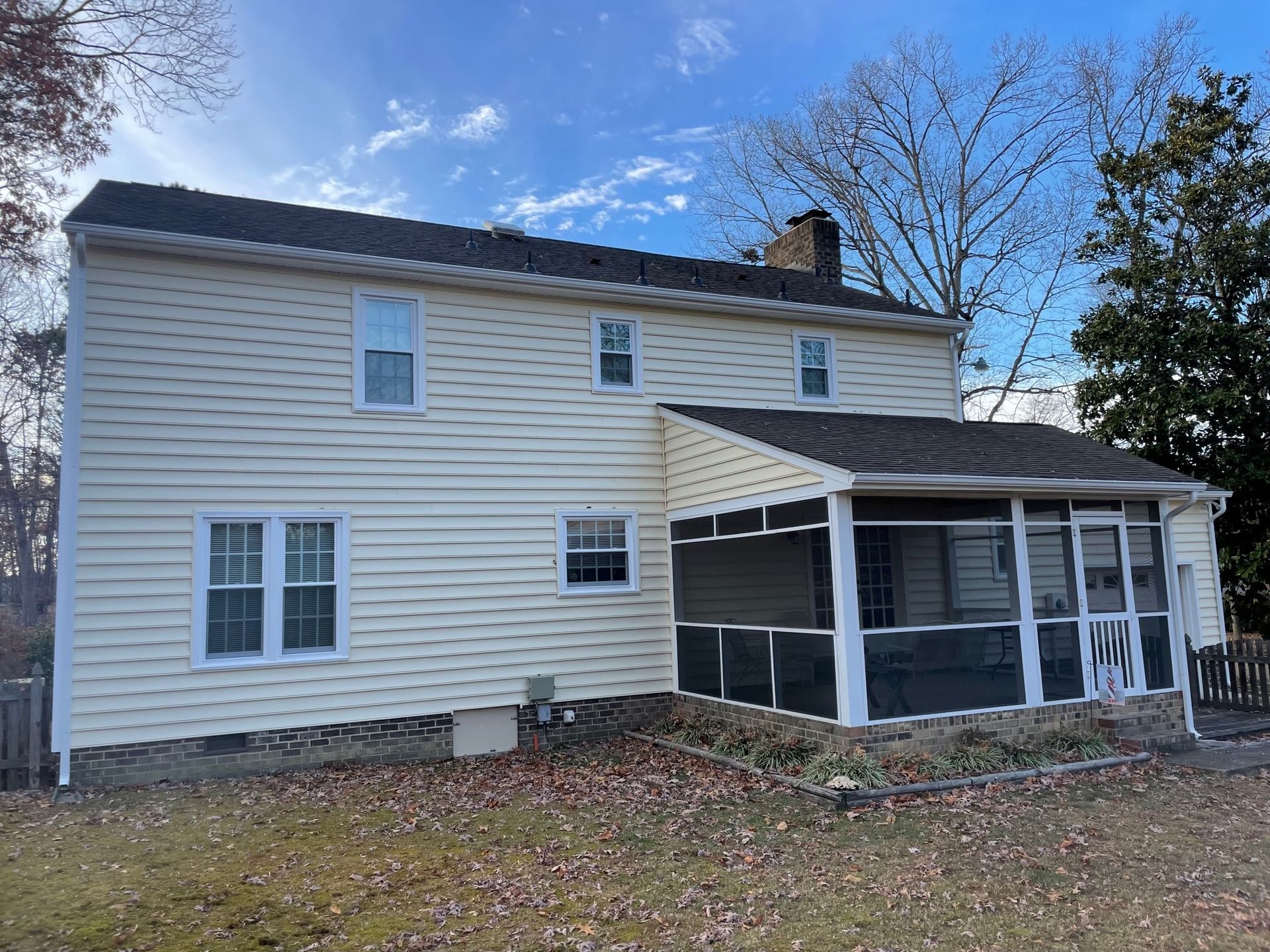The back of a white house with a screened in porch.