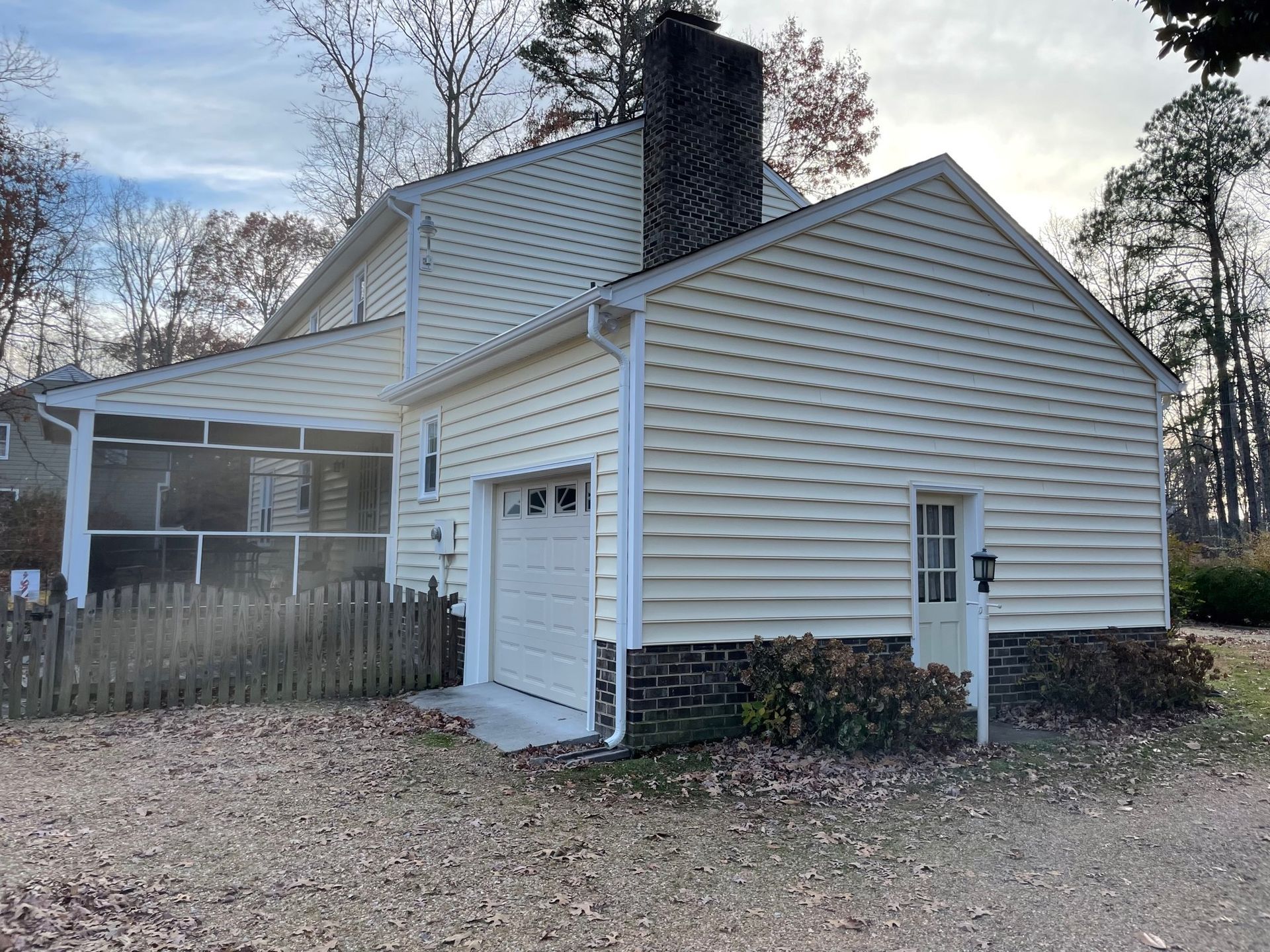 A white house with a garage and a screened in porch.