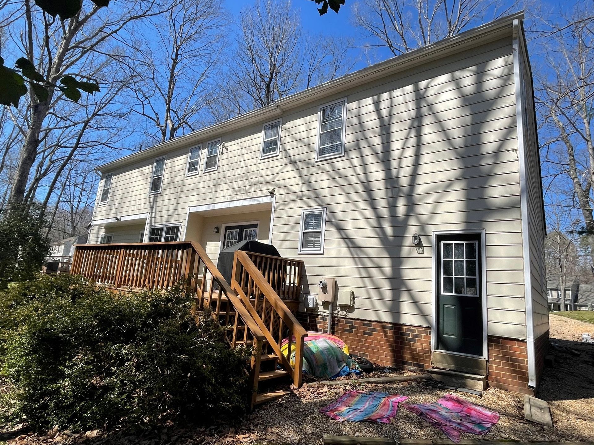 The back of a white house with a wooden deck and stairs.