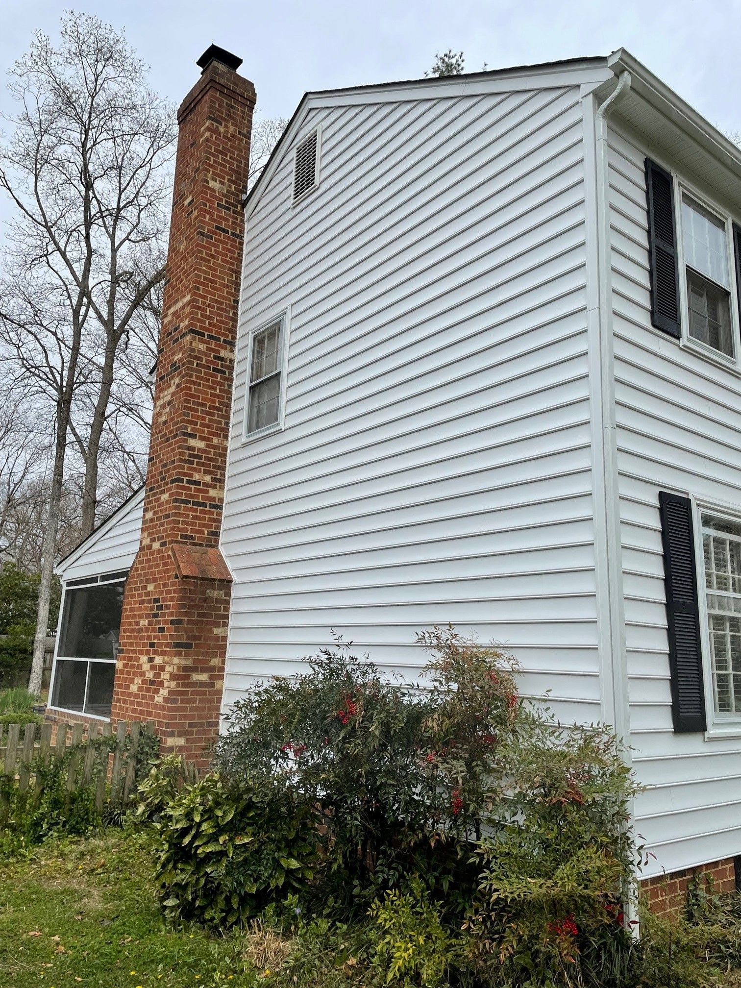 A white house with a brick chimney on the side of it.