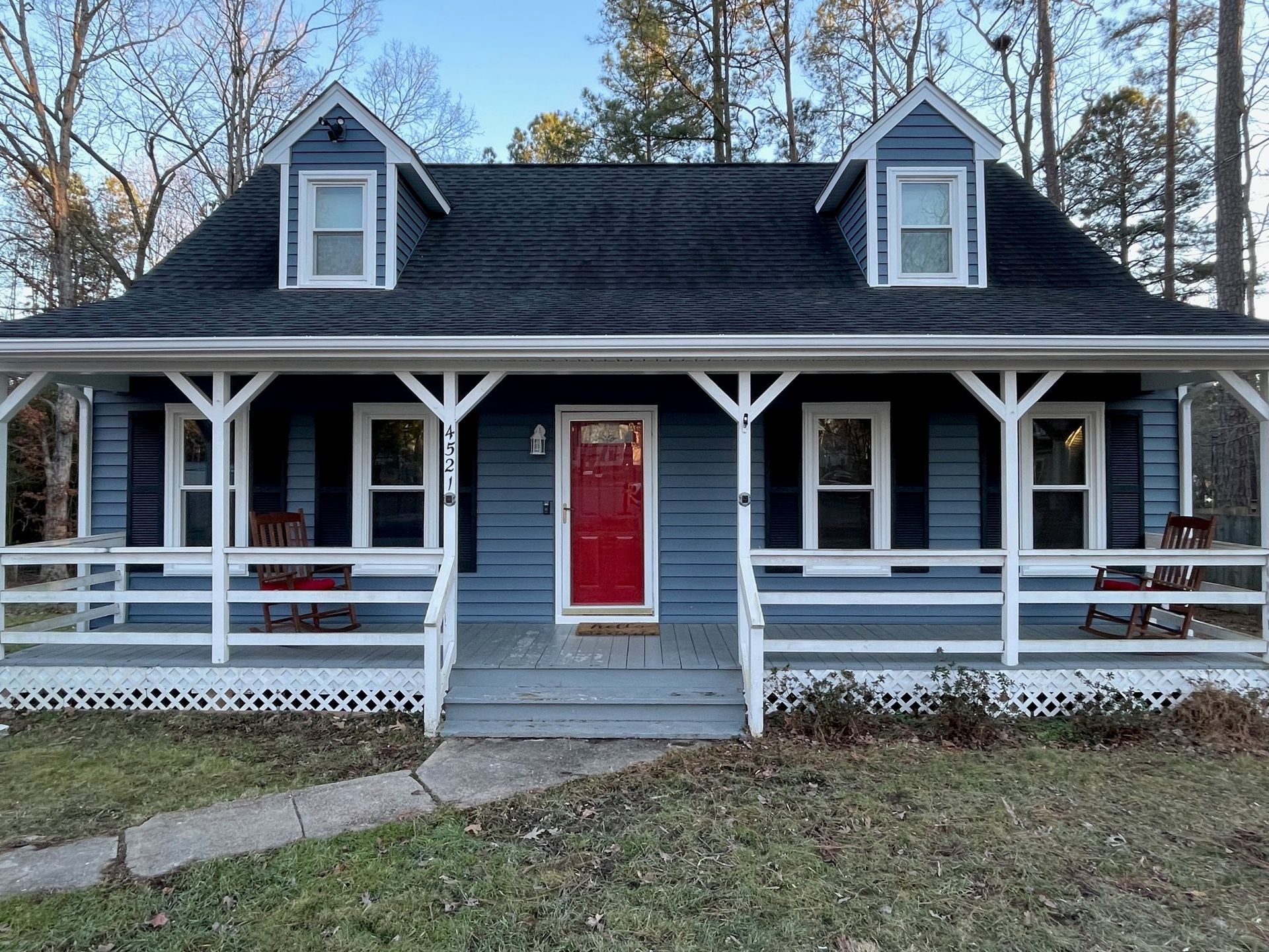 A blue house with a red door and a porch.