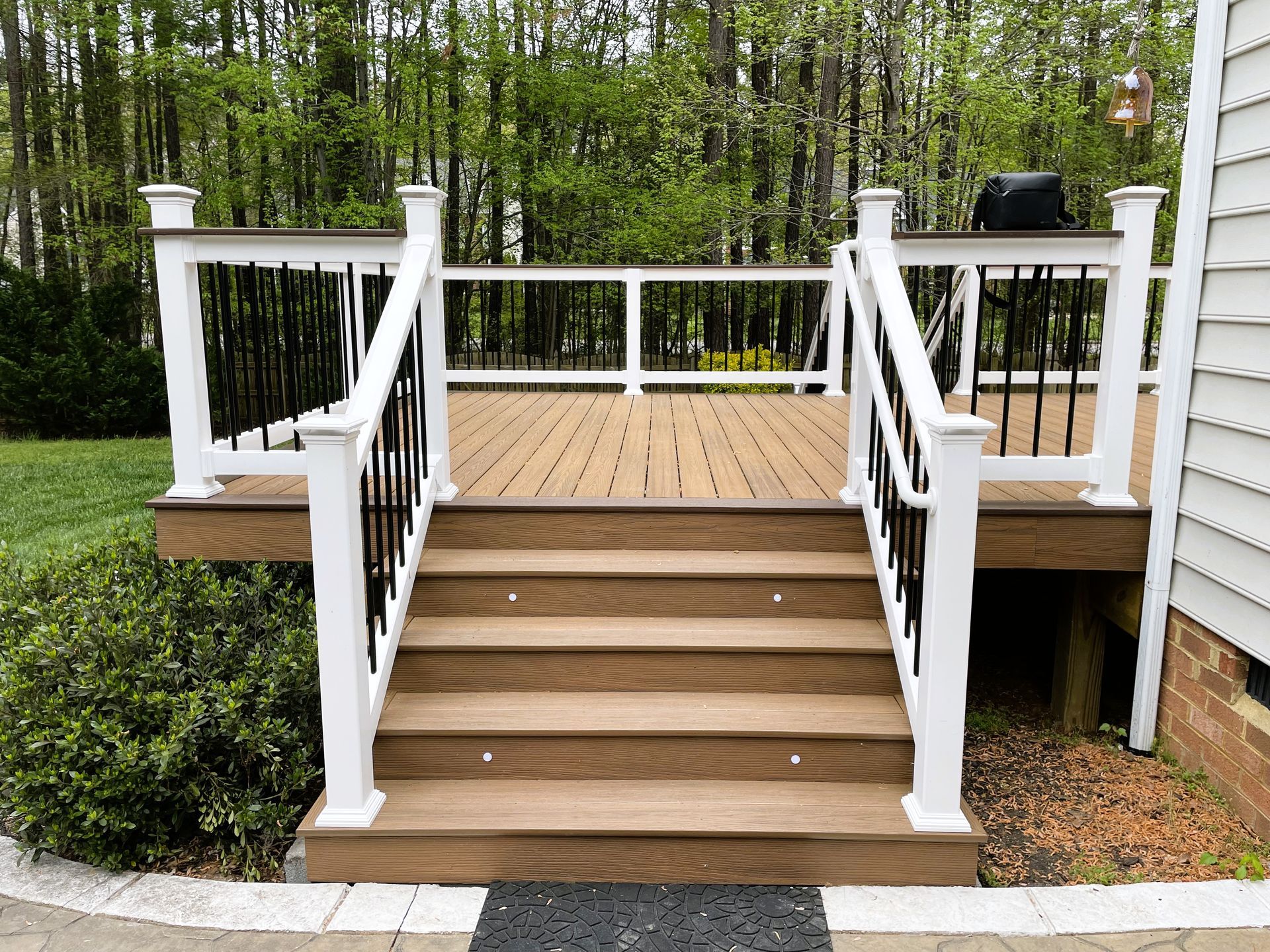 A wooden deck with stairs leading up to it and a white railing.