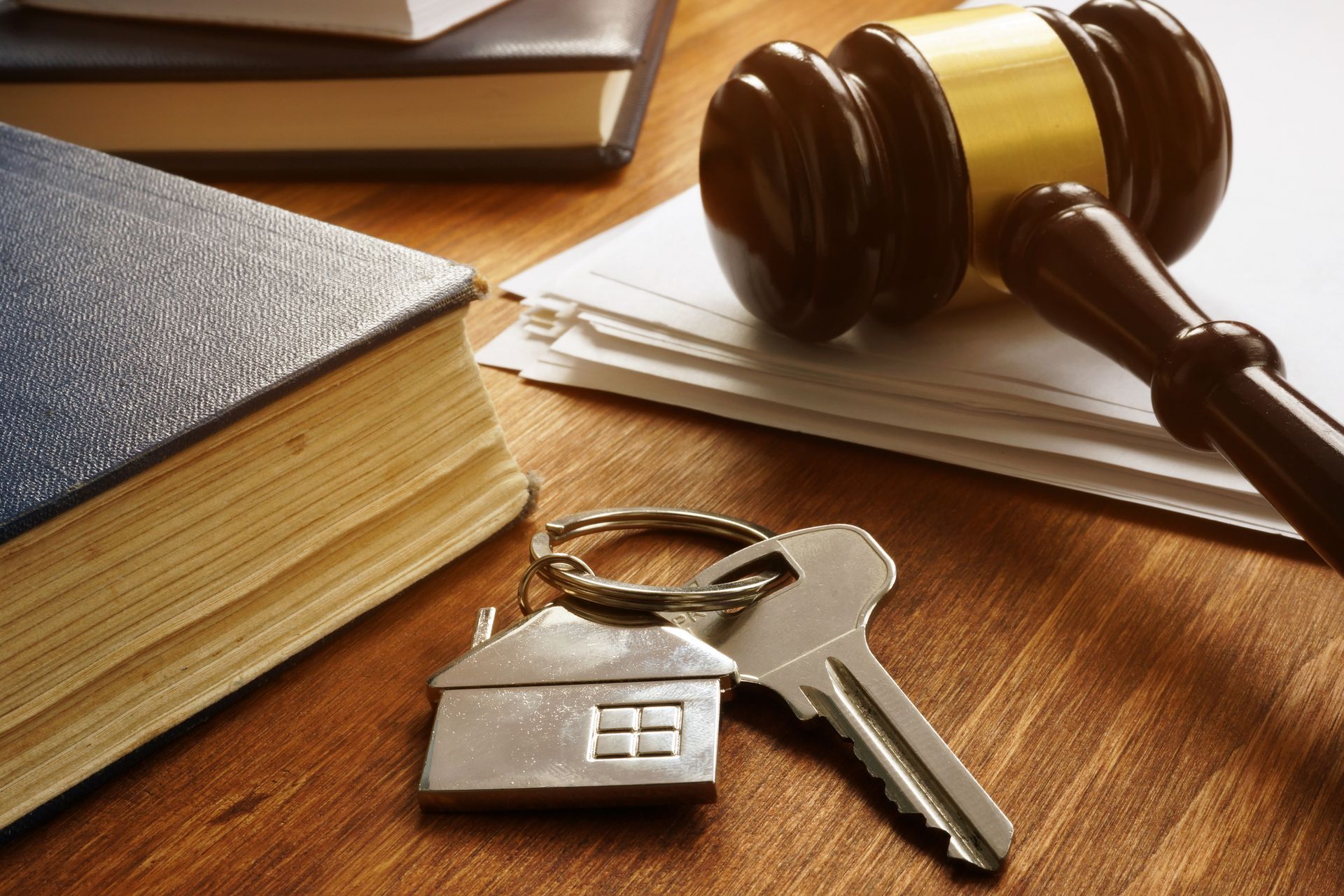 A pair of keys sitting on top of a wooden table next to a judge 's gavel.