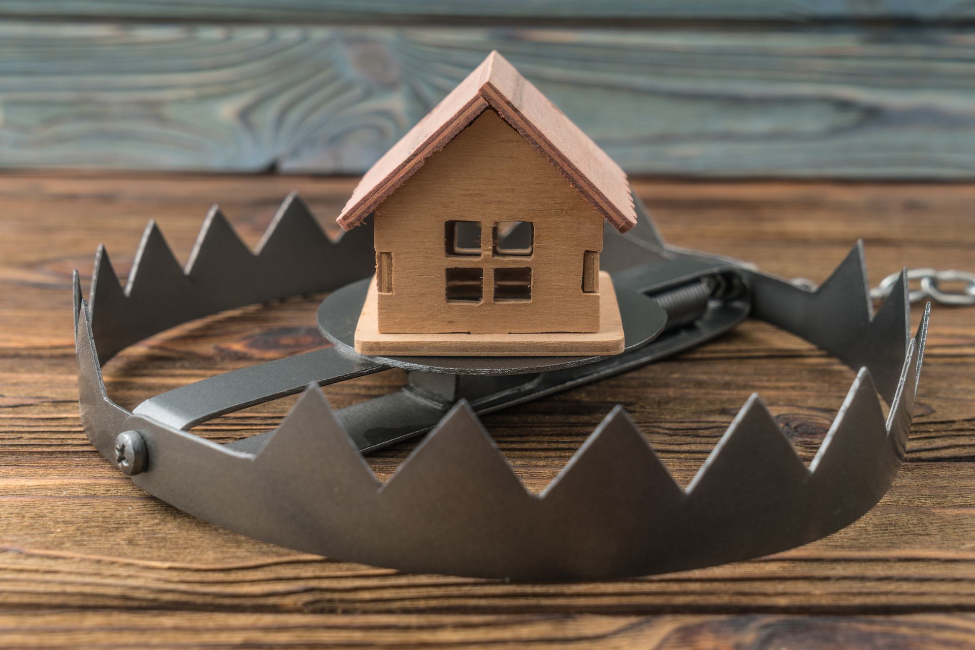 A small house is sitting on top of a bear trap on a wooden table.