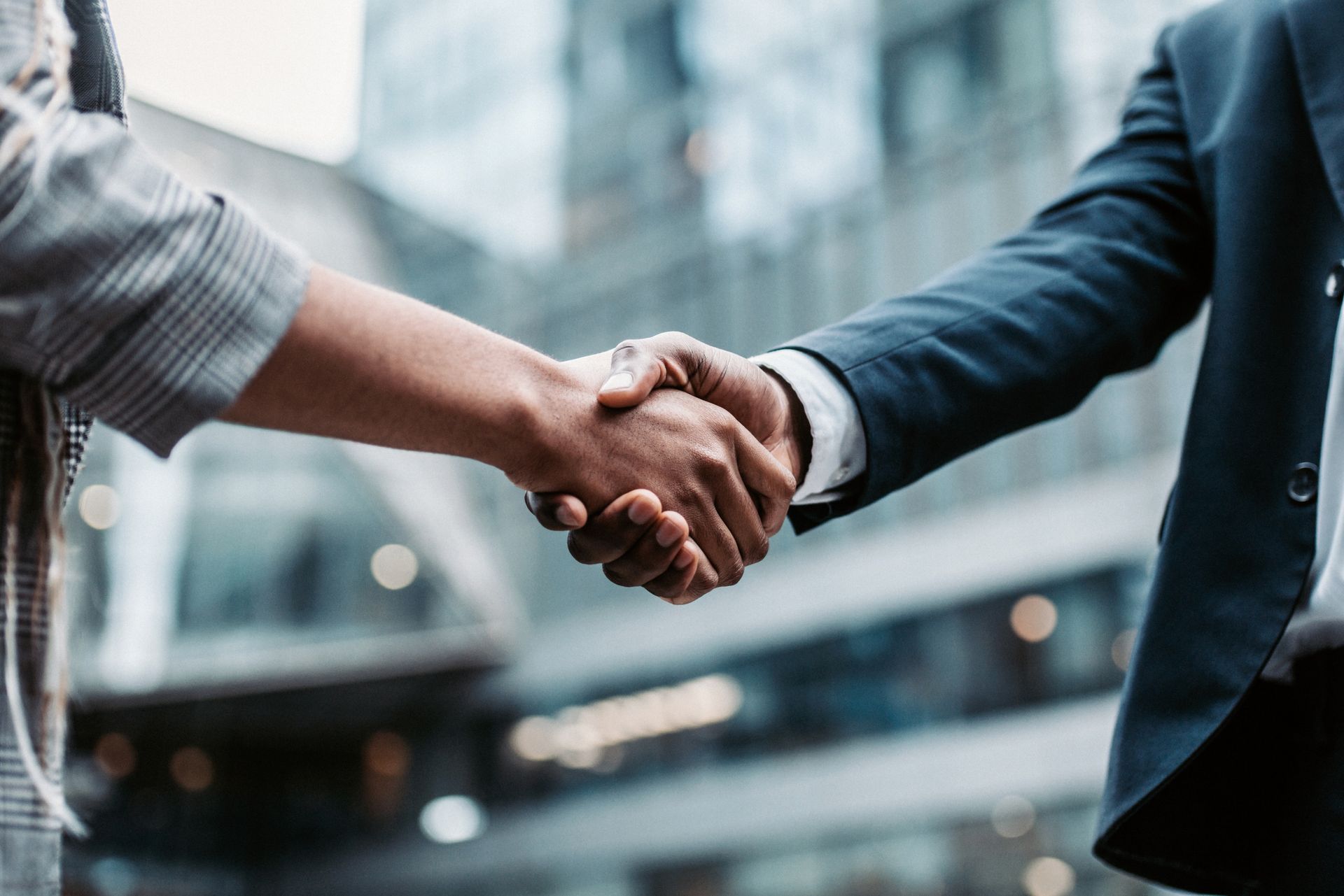 A man and a woman are shaking hands in front of a building.
