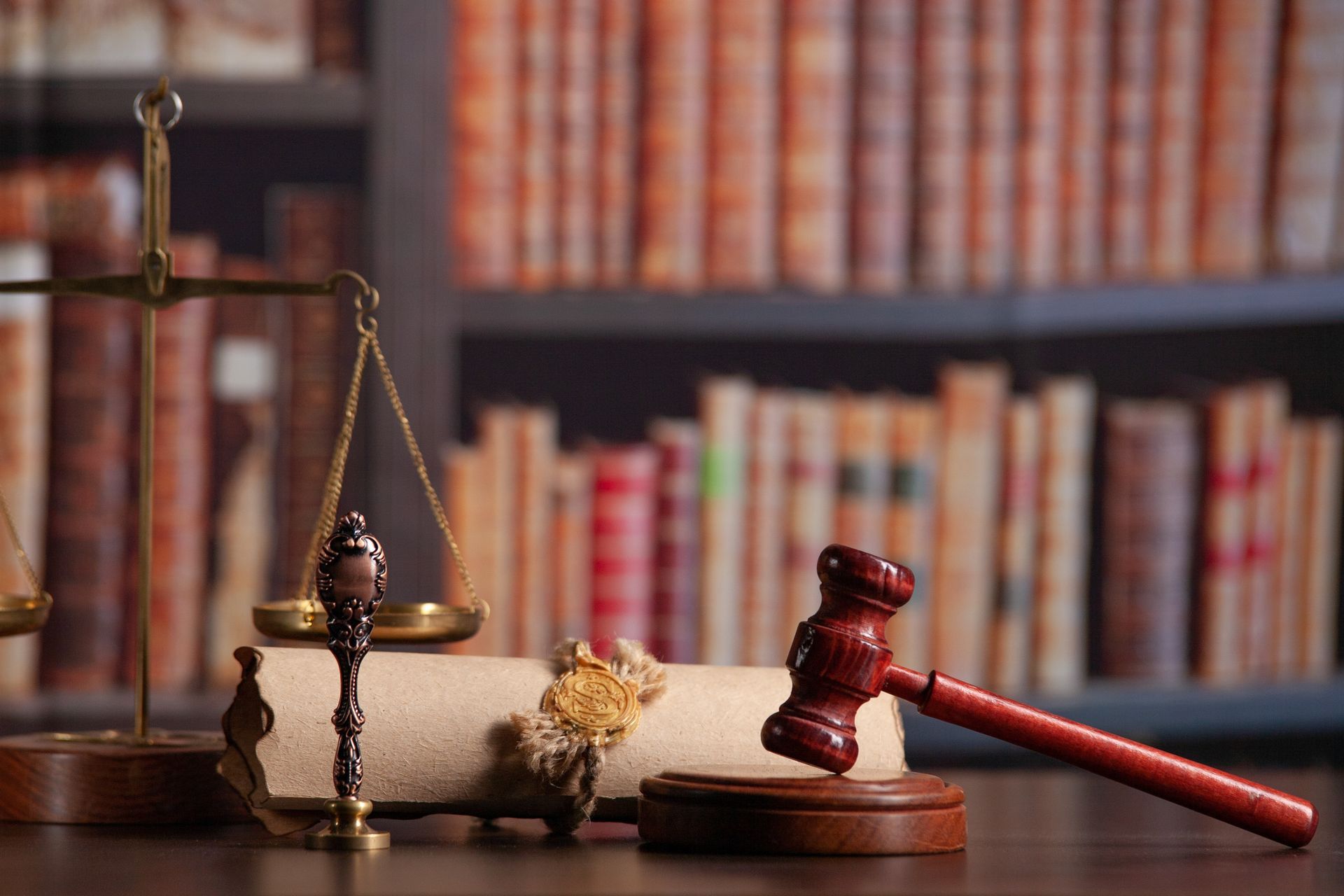 A judge 's gavel , scales of justice , and a book on a table in a library.