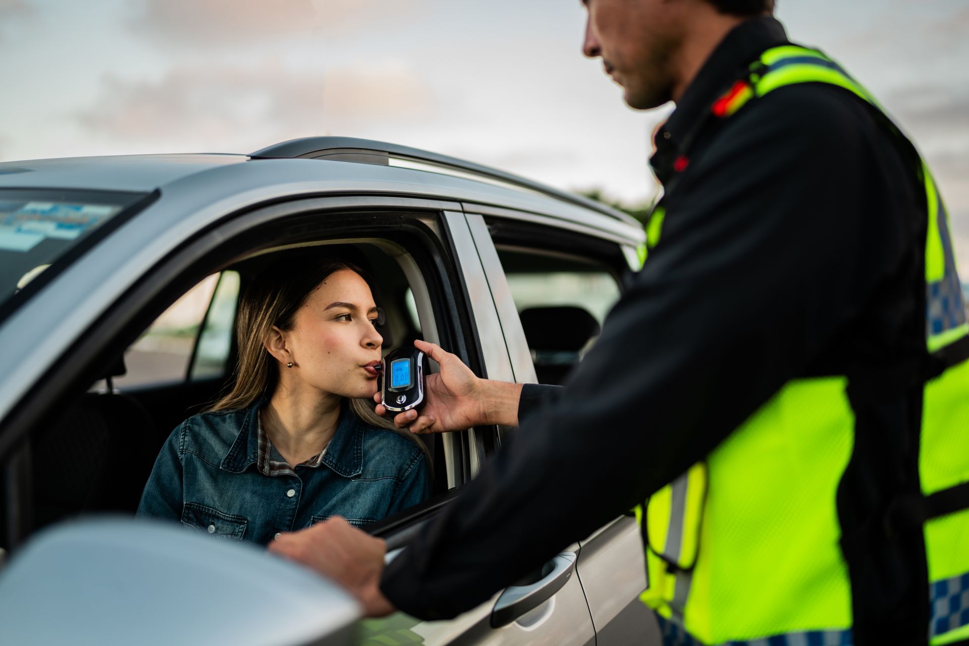 A woman is being tested for alcohol by a police officer in a car.