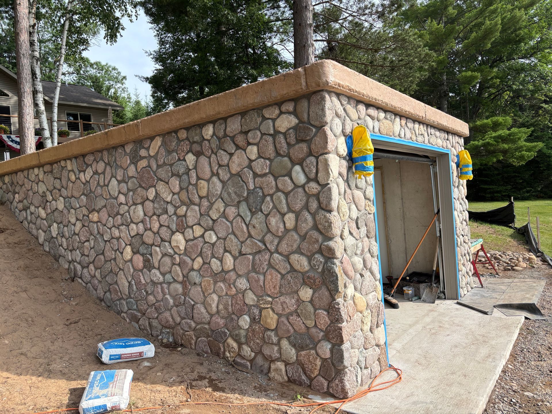 Stone retaining wall with a garage entrance, concrete driveway.