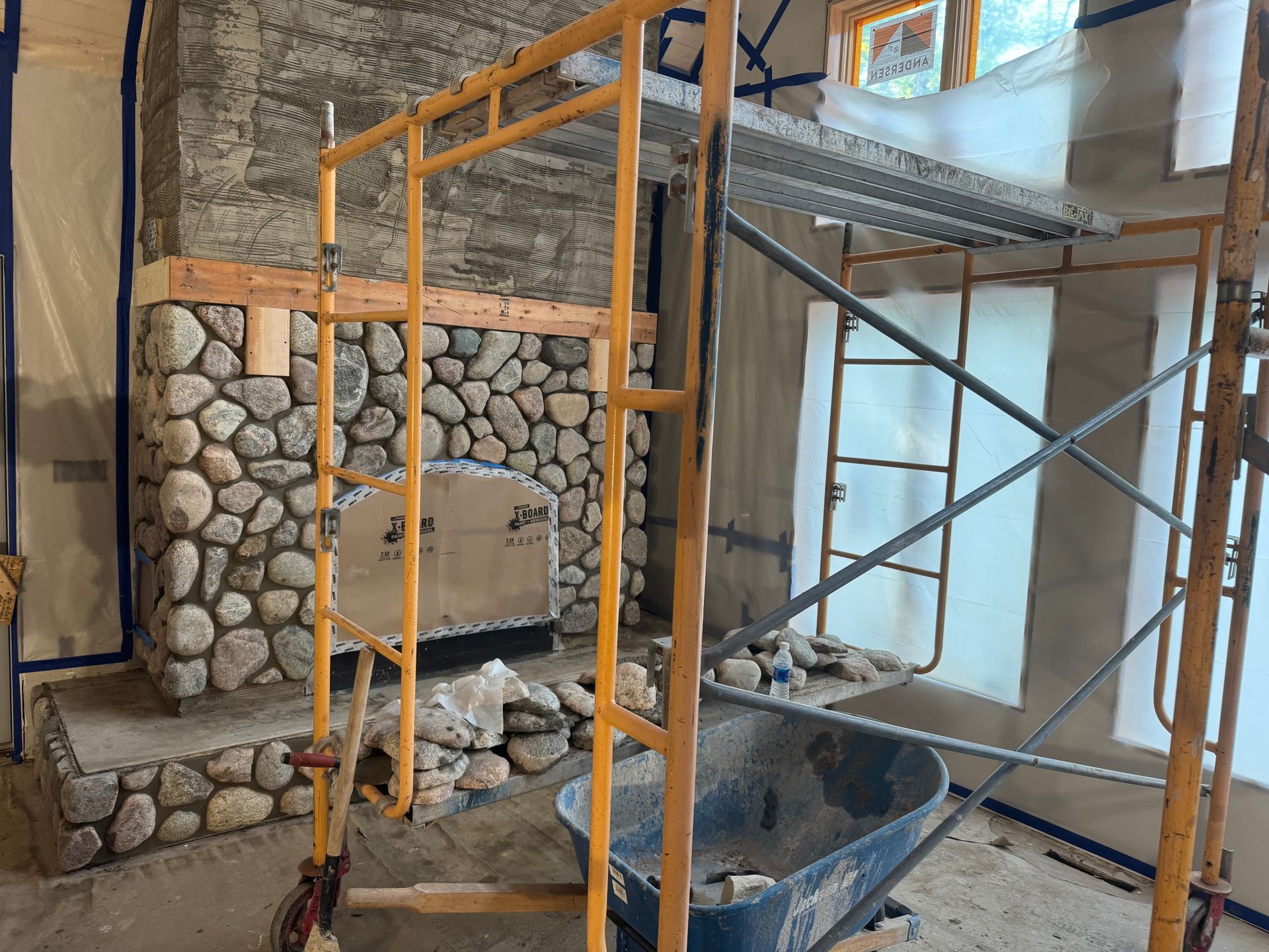 Stone fireplace under construction with scaffolding.