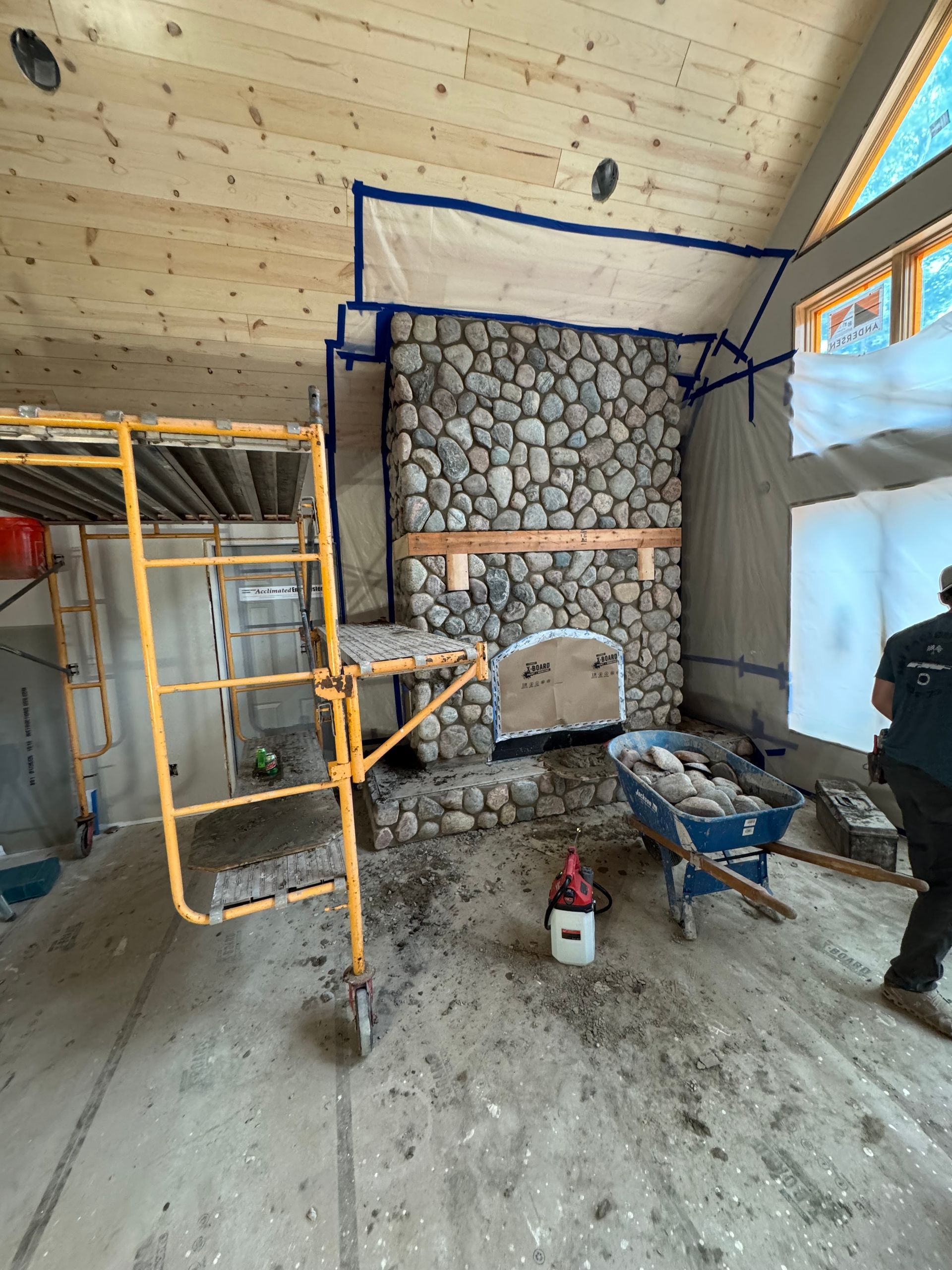 Stone fireplace under construction with scaffolding.
