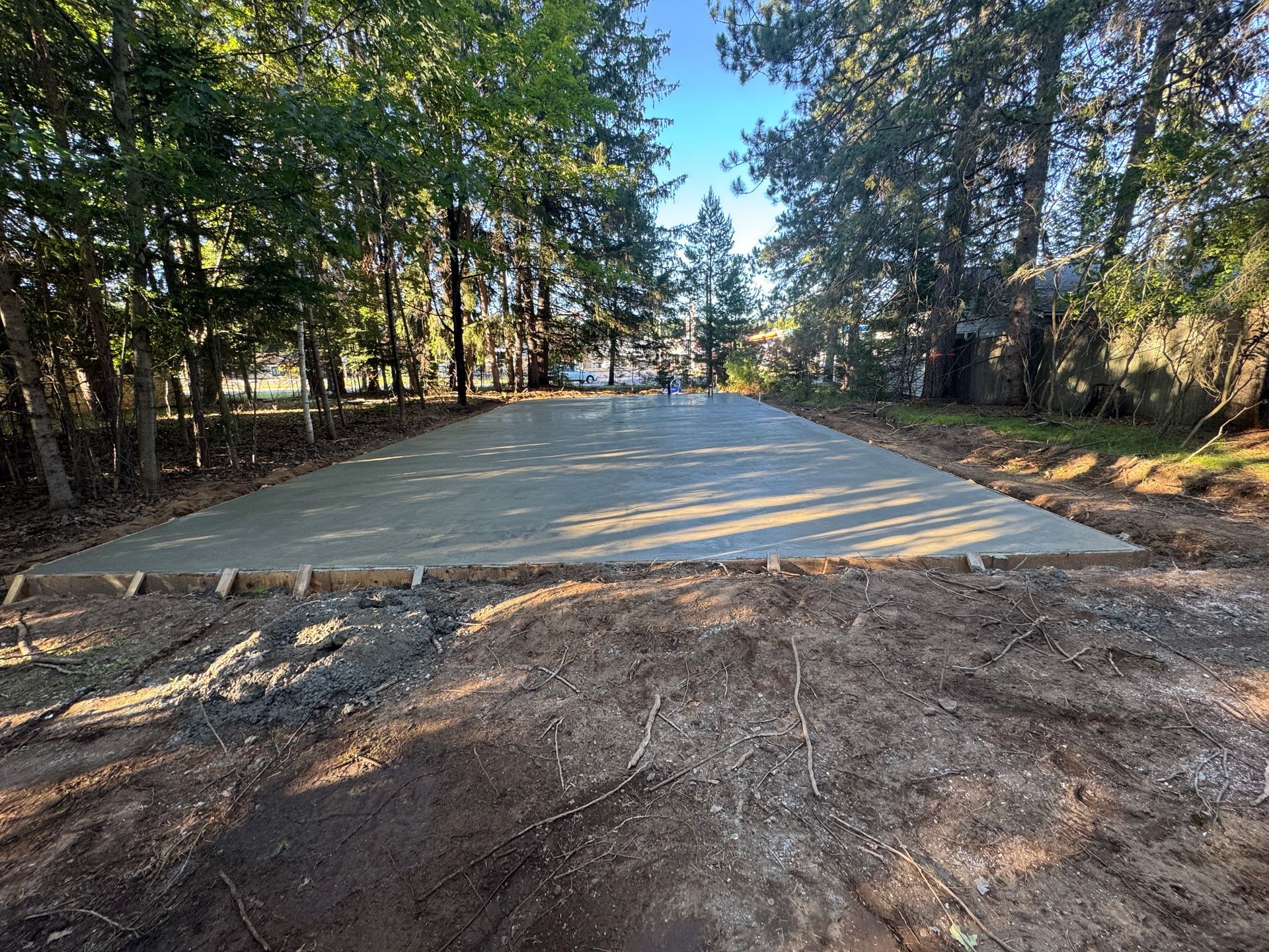 Newly poured concrete slab in a wooded area; ready for construction.