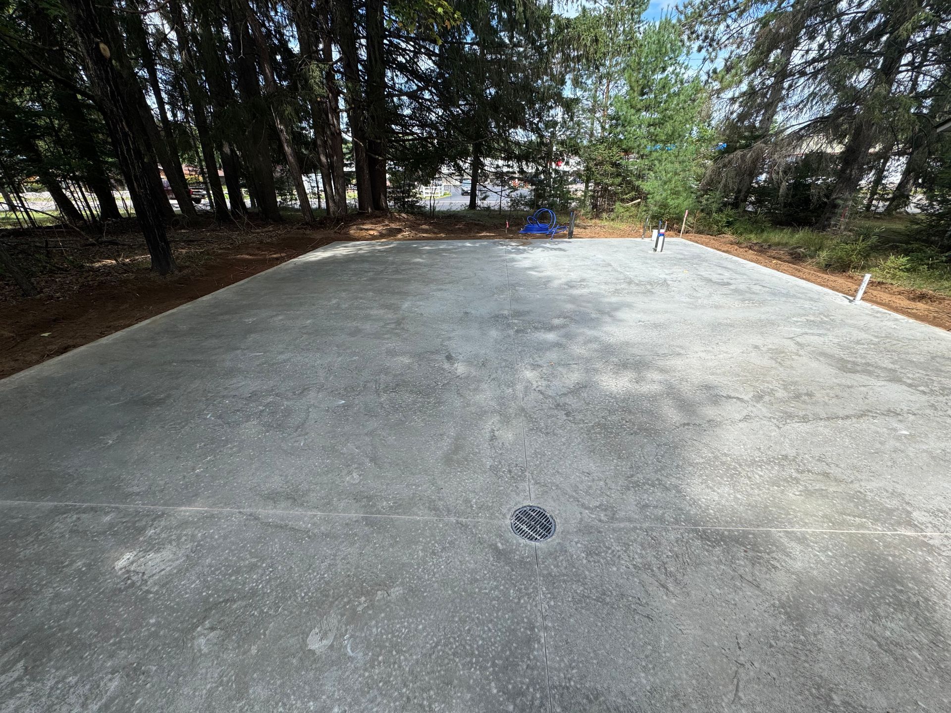 Concrete slab, possibly for a foundation, surrounded by trees.