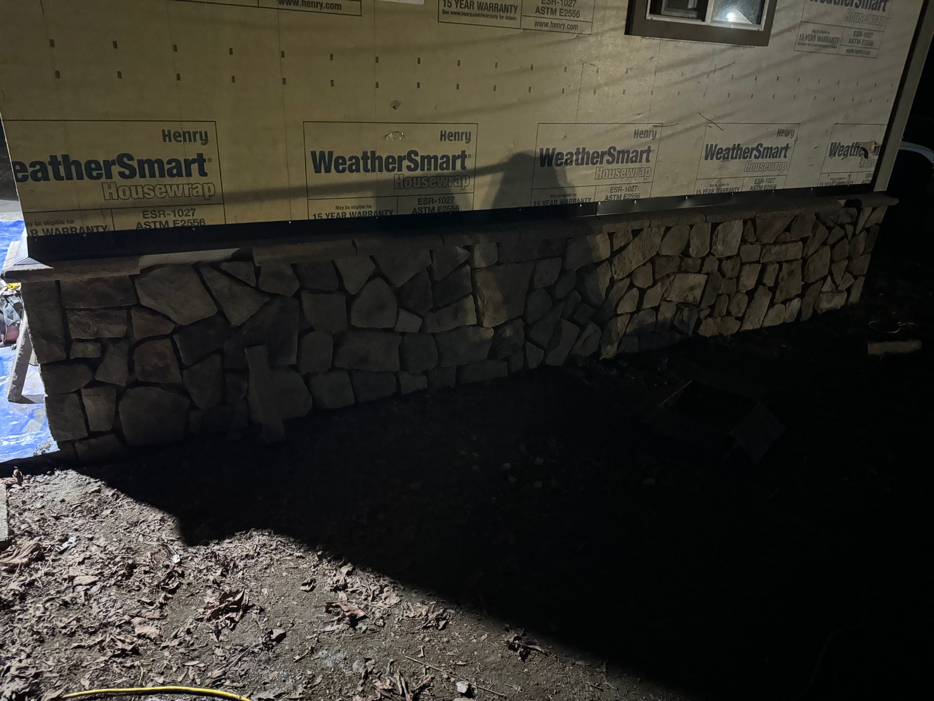 Stone veneer on the base of a building under construction, with dark surroundings.