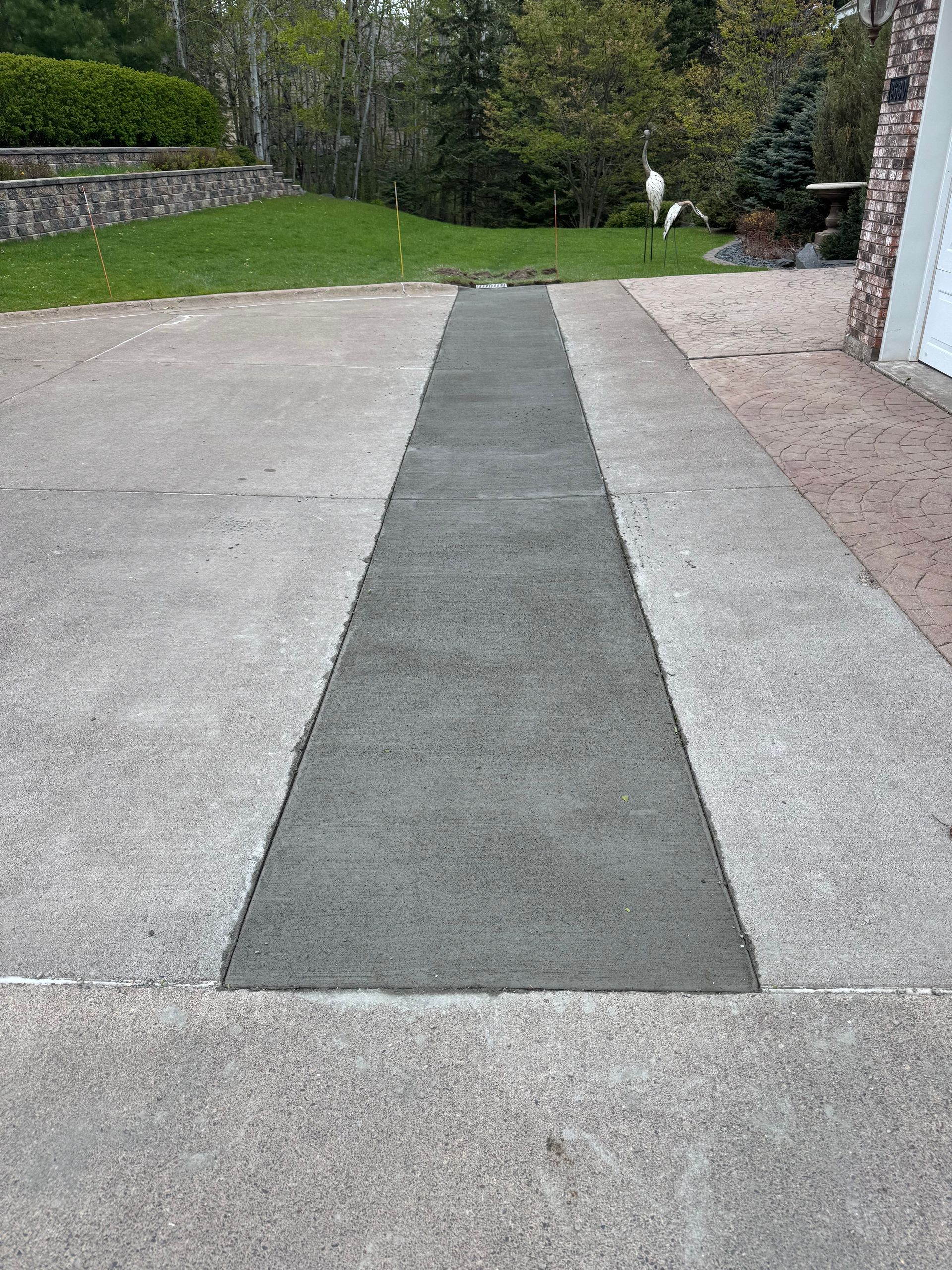 Concrete driveway with a newly poured strip of concrete down the center.