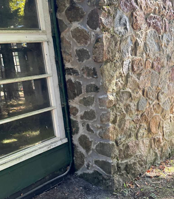 Corner of a stone building, next to a green-trimmed window.