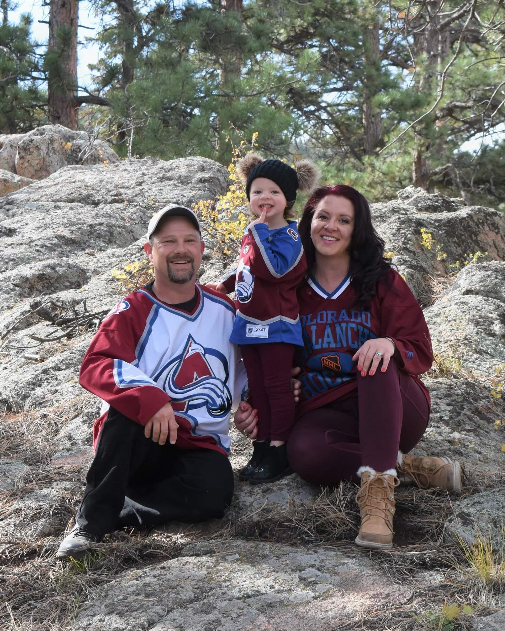 A man , woman and child are posing for a picture on a rock.