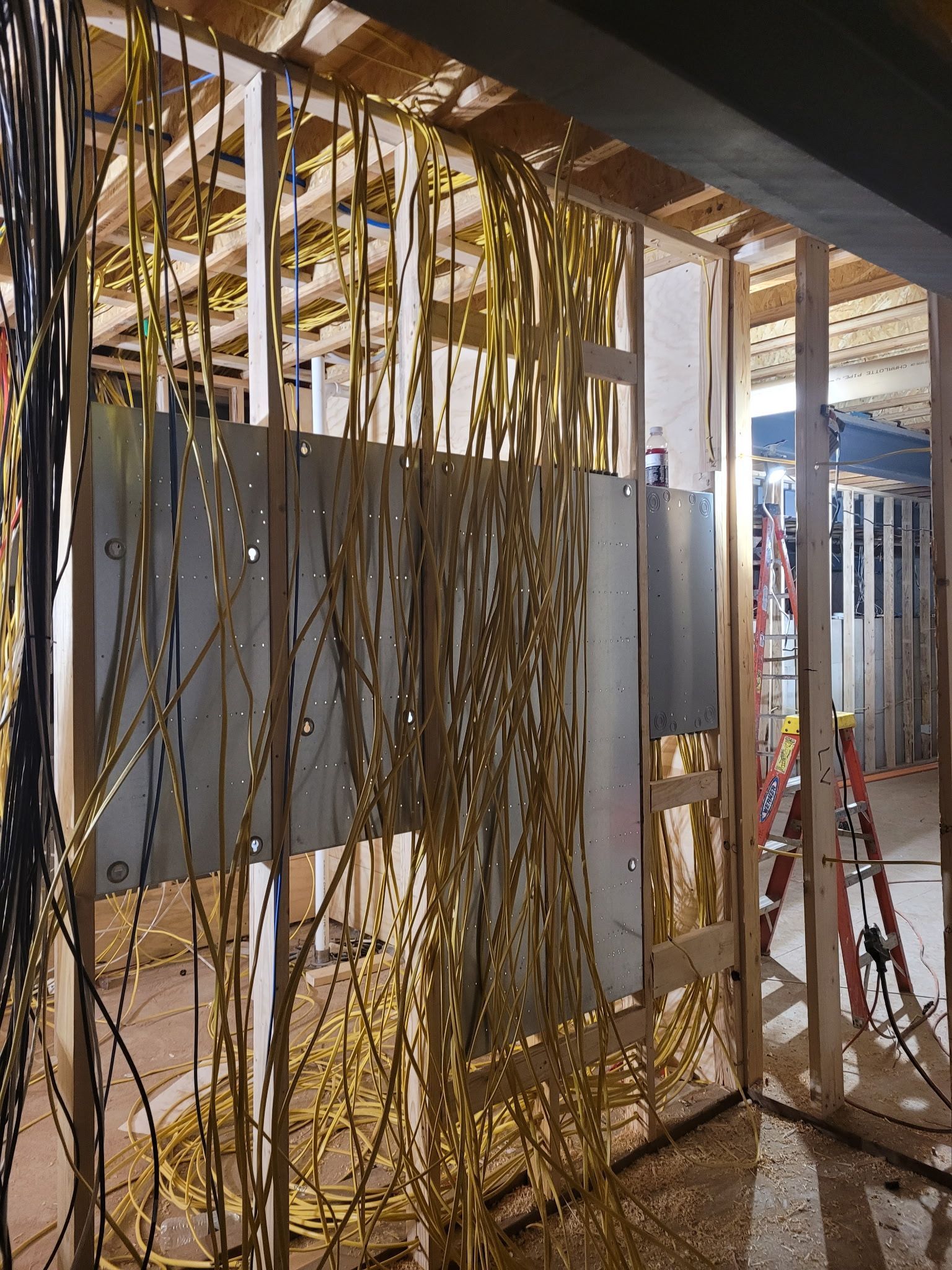A room under construction with a lot of wires hanging from the ceiling.