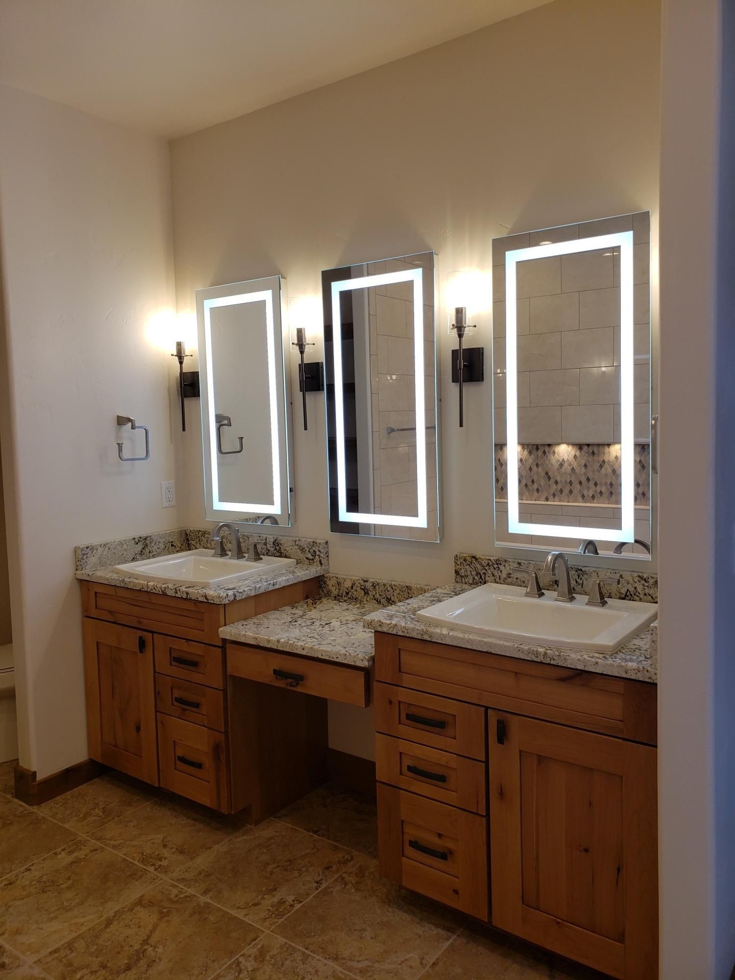 A bathroom with two sinks and three mirrors.