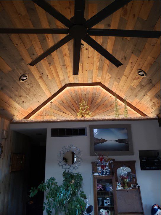 A living room with a wooden ceiling and a ceiling fan