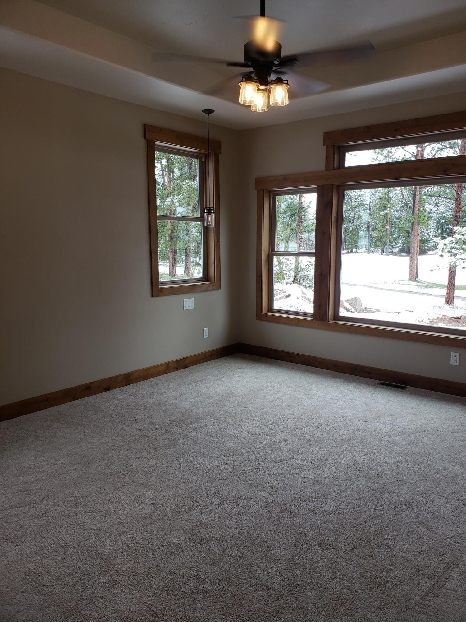 An empty room with a ceiling fan and lots of windows