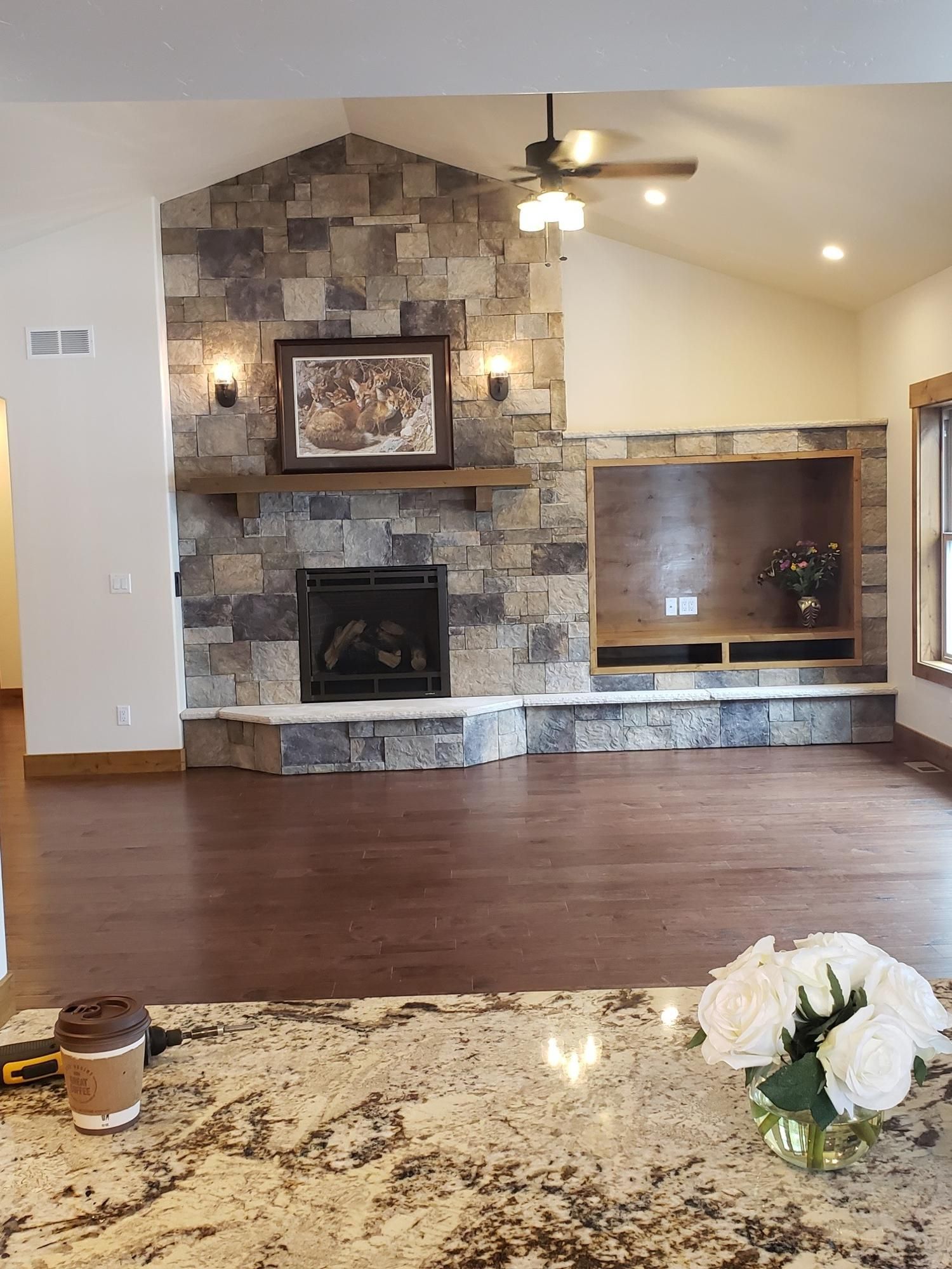 A living room with a fireplace and a ceiling fan