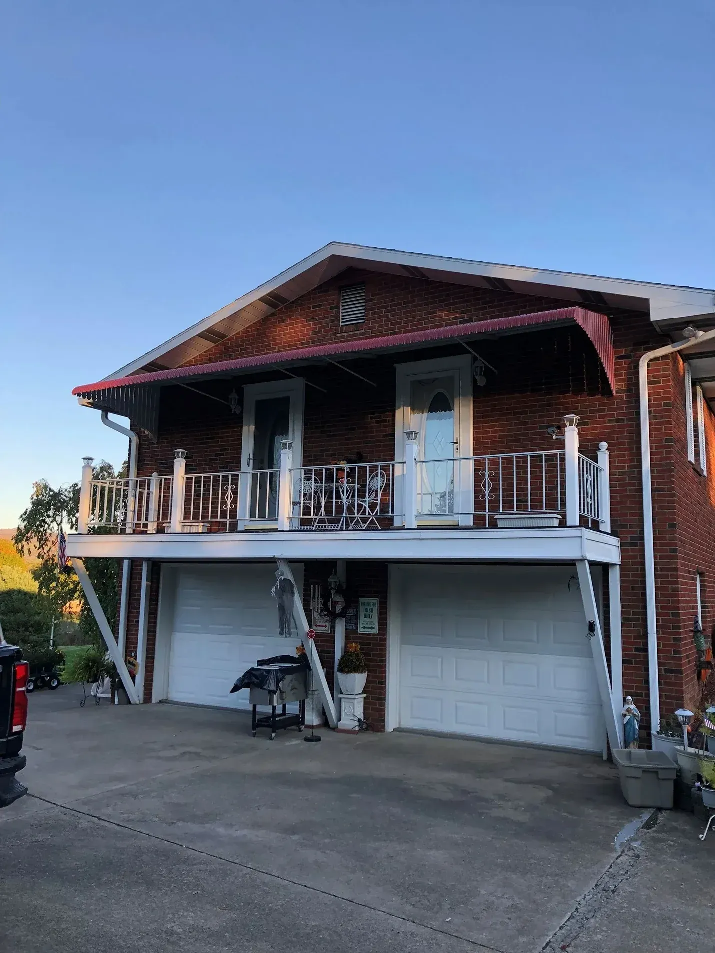 Two-story brick building with white garage doors and a balcony. Blue sky overhead.