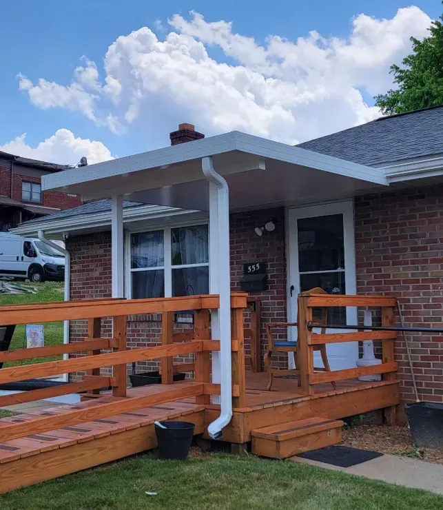 Front of a brick house with a white awning, wooden porch, and wheelchair ramp.