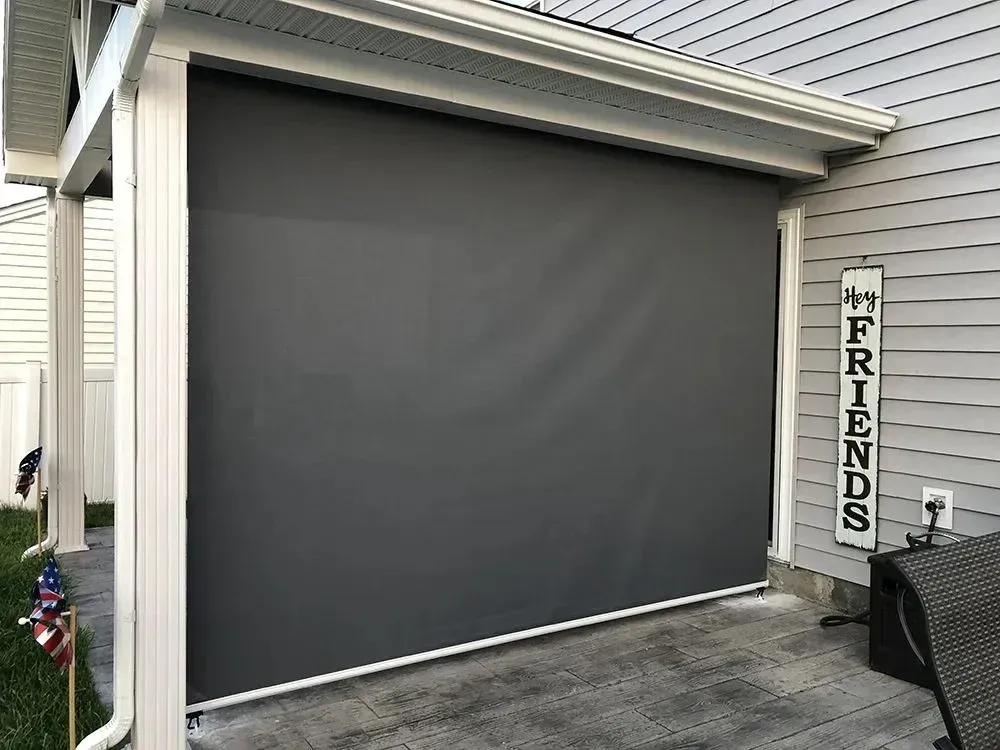 Gray retractable outdoor shade on a patio, attached to a house with a 